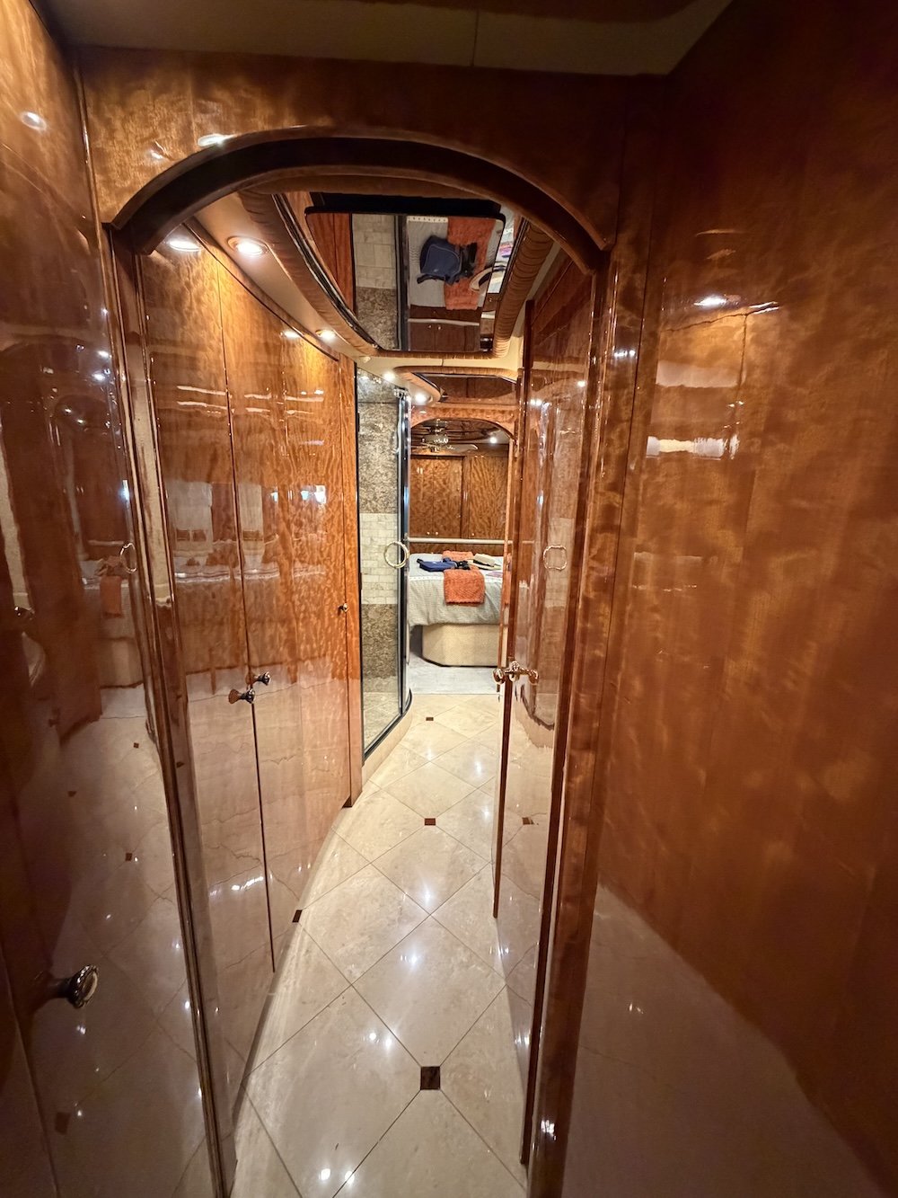 Luxury coach hallway lined with polished burl wood closets.