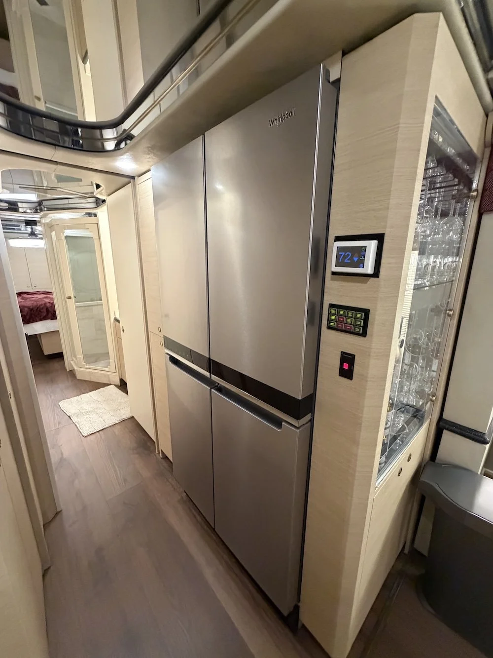 Hallway with closets, mirrored doors, fridge, and thermostat.