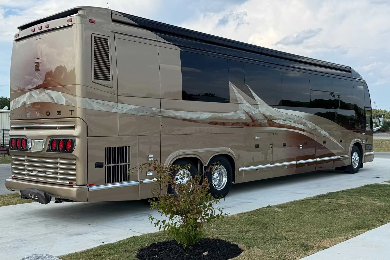 Rear driver-side view of the coach showing the Prevost badge and taillights.