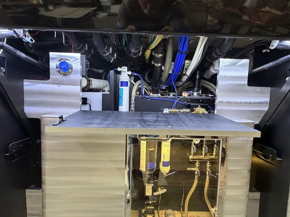 Interior view of an RV storage compartment with various components and metallic panels.
