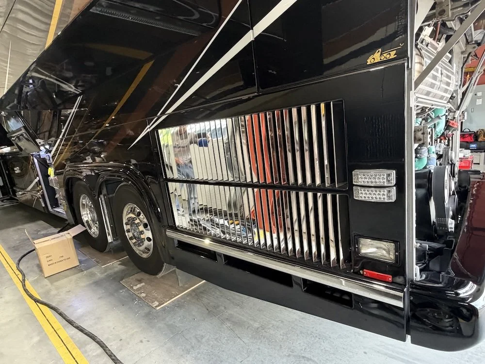 Close-up of a large black and gold luxury motorhome inside a warehouse or garage.