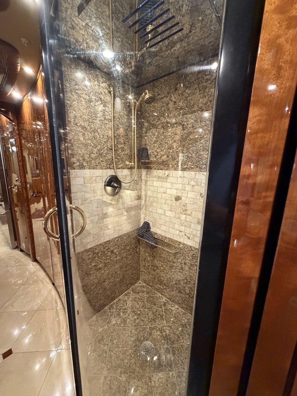 Tiled walk-in shower with glass doors inside the luxury coach bathroom.