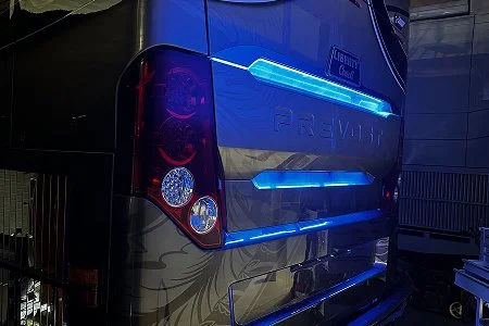 Rear view of a luxury motorcoach at night showcasing custom, high-intensity blue lighting.