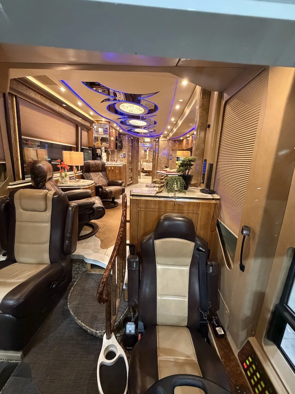 Inside a luxurious RV with leather captain's chairs, decorative lighting, and a cozy, well-furnished living area.