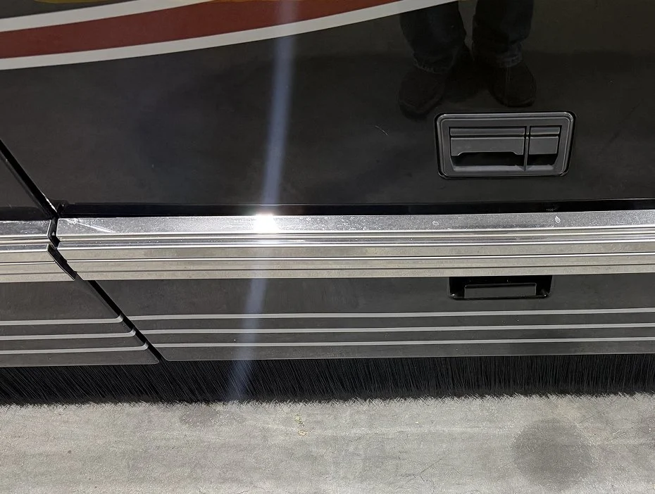 Full rear view of a custom-painted motorcoach featuring upgraded chrome-style stainless steel rub rails.