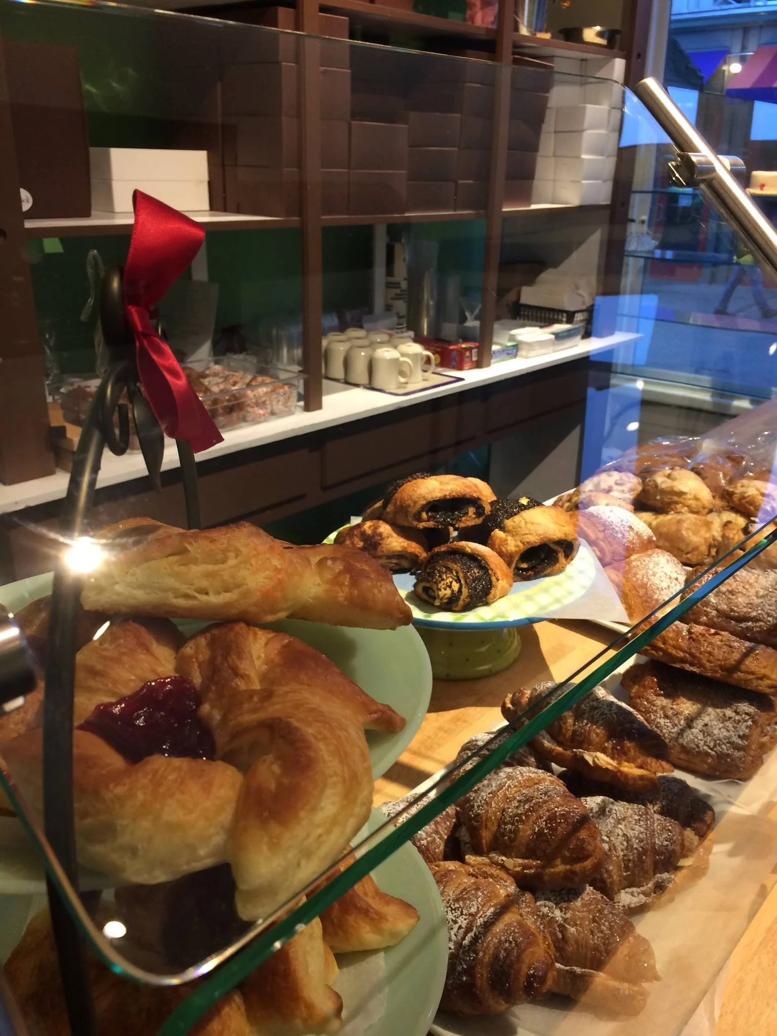 Bakery display with a variety of pastries, including croissants, jam-filled pastries, and chocolate rolls.