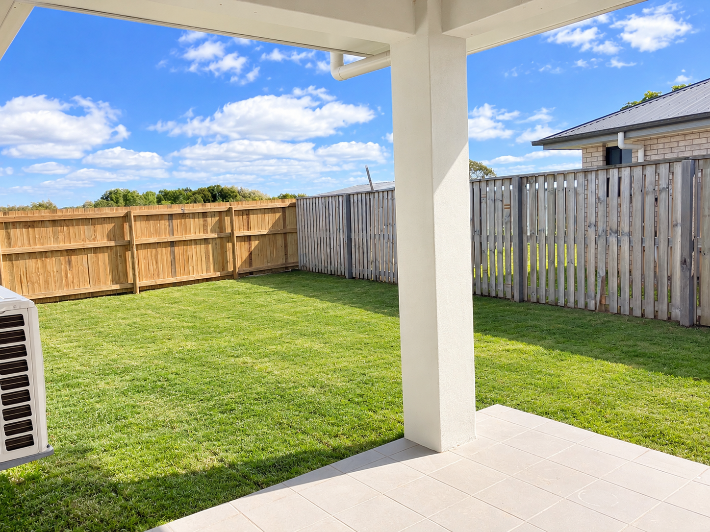 Sunny Patio Overlooking Fenced Backyard.png