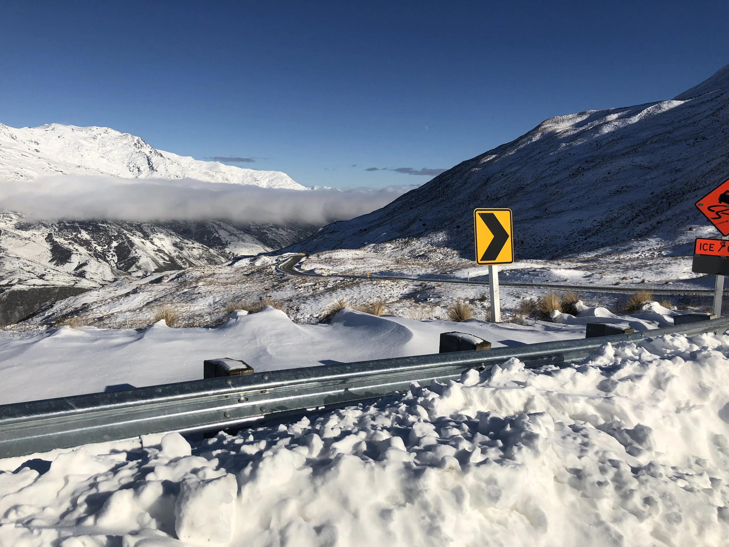 Snow-covered mountain landscape with road signs and guardrail