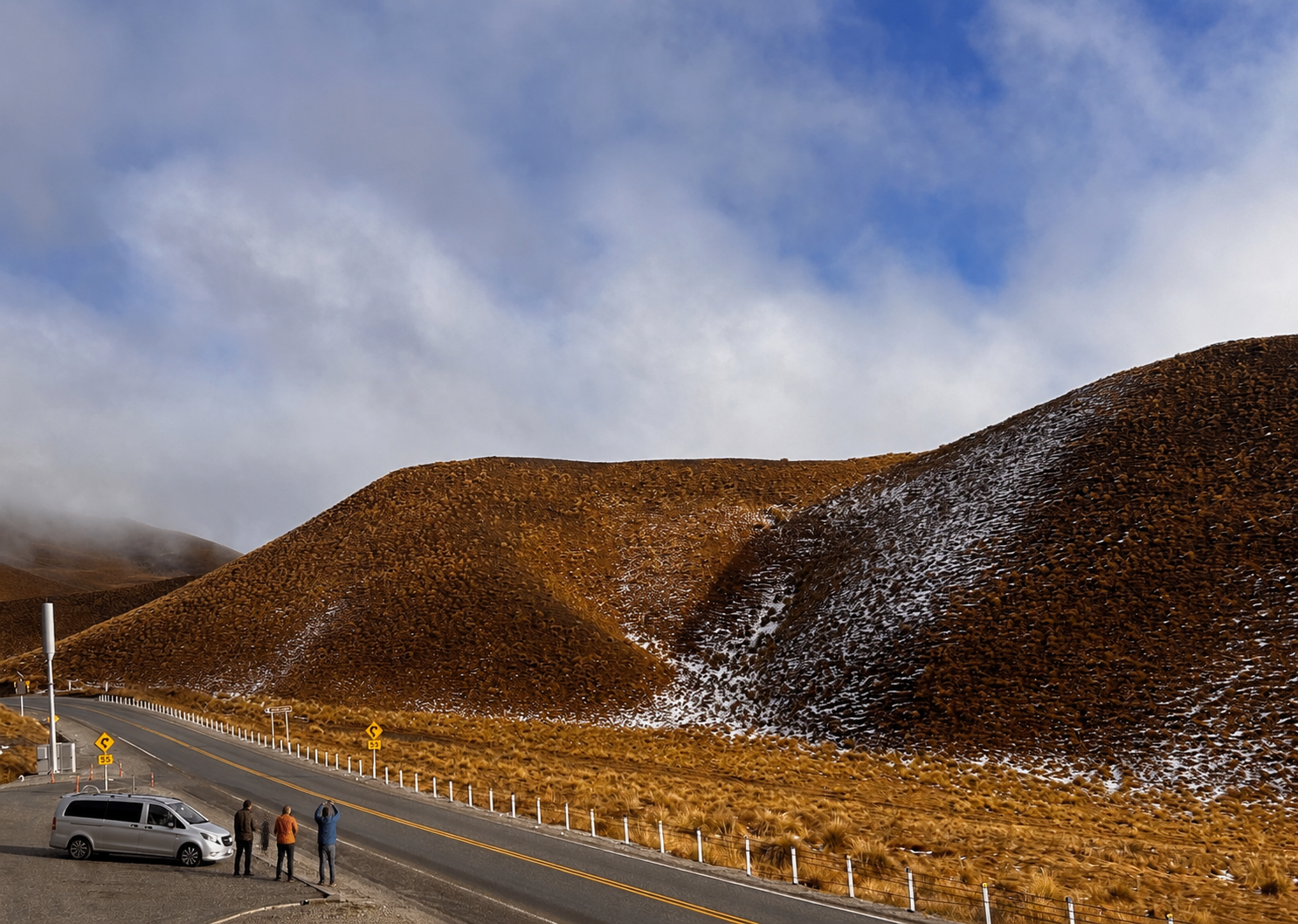 Local guide showing two guests the Lindis Pass view beside a silver Mercedes Vito