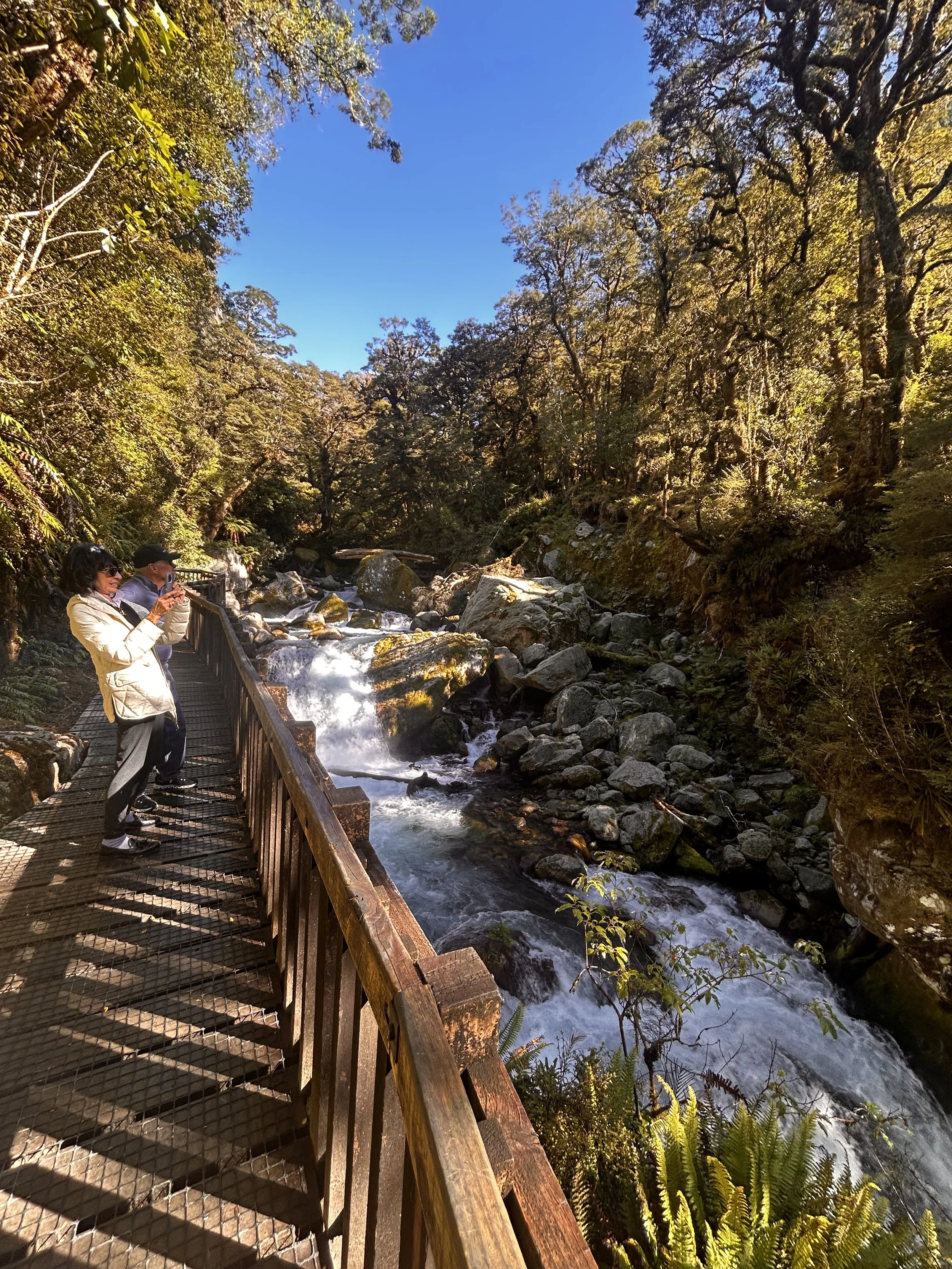 People taking photos on a wooden bridge over a river at Marion Falls
