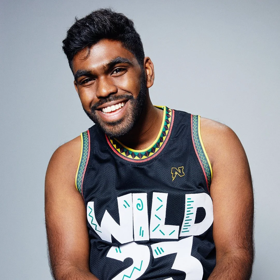 Young man smiling, wearing a black sleeveless sports jersey with colorful tribal patterns around the collar and armholes, and the words 'WILD SOUL' written in bold letters on the front.