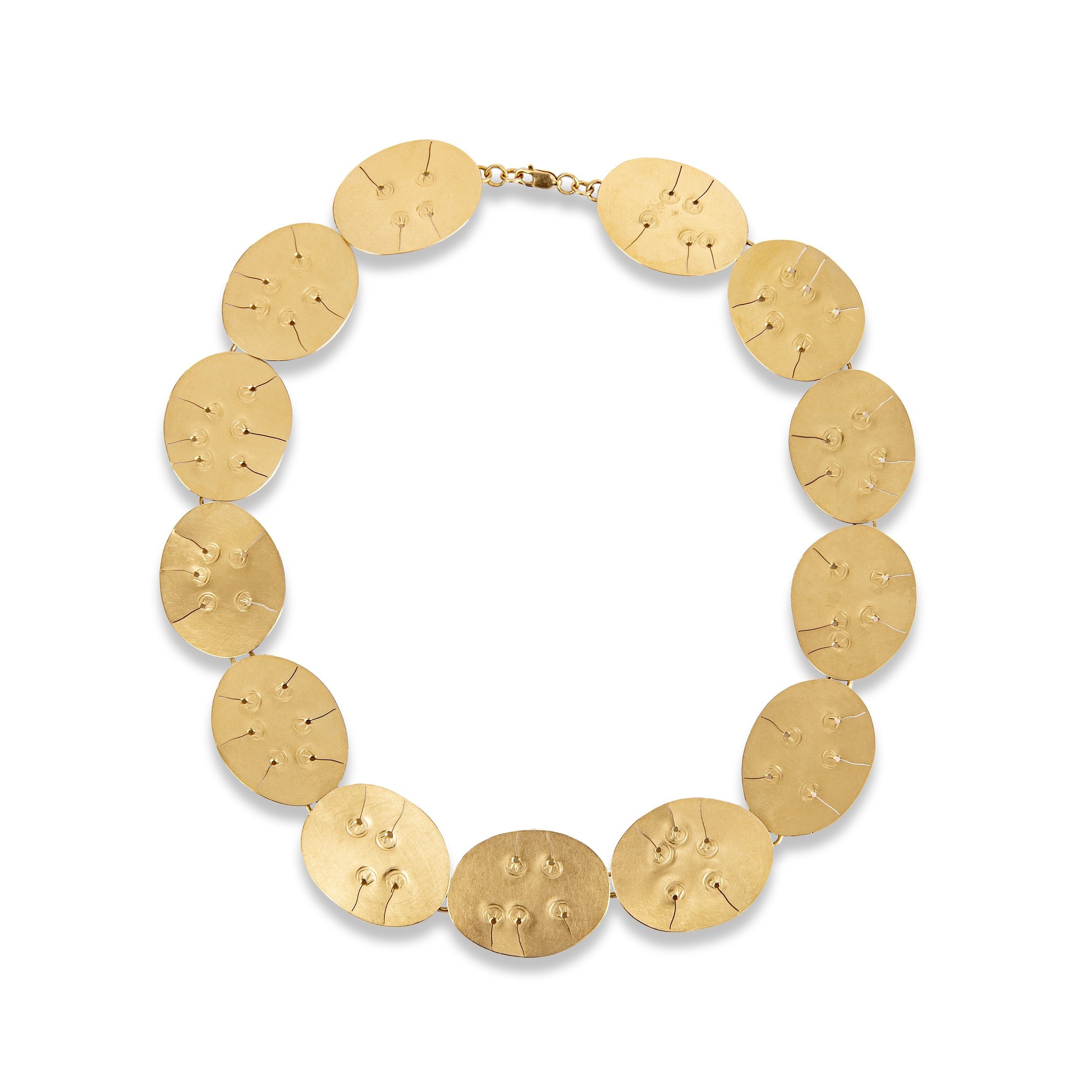 Gold oval-shaped statement necklace with textured surface and attached pins, on a white background.