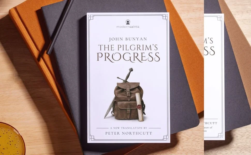 Book titled "The Pilgrim's Progress" by John Bunyan on top of a gray notebook and a brown folder, with a black pen resting on the notebook, all placed on a wooden surface.