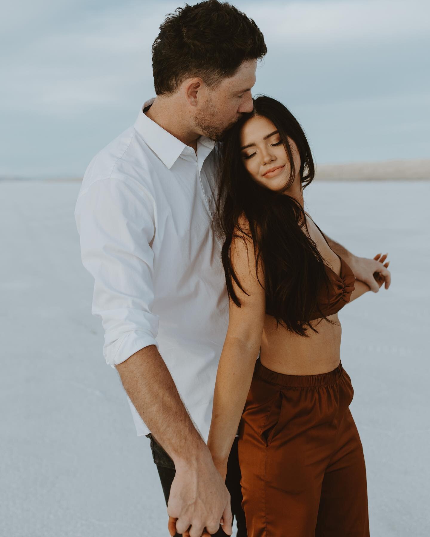 -
The salt flats stretch out, so vast and so wide,
A landscape so stunning, it's hard to decide,
Where to snap photos of this couple in love,
With the sun setting low, and the sky up above.

The white of the salt, so pure and so bright,
Reflects the 