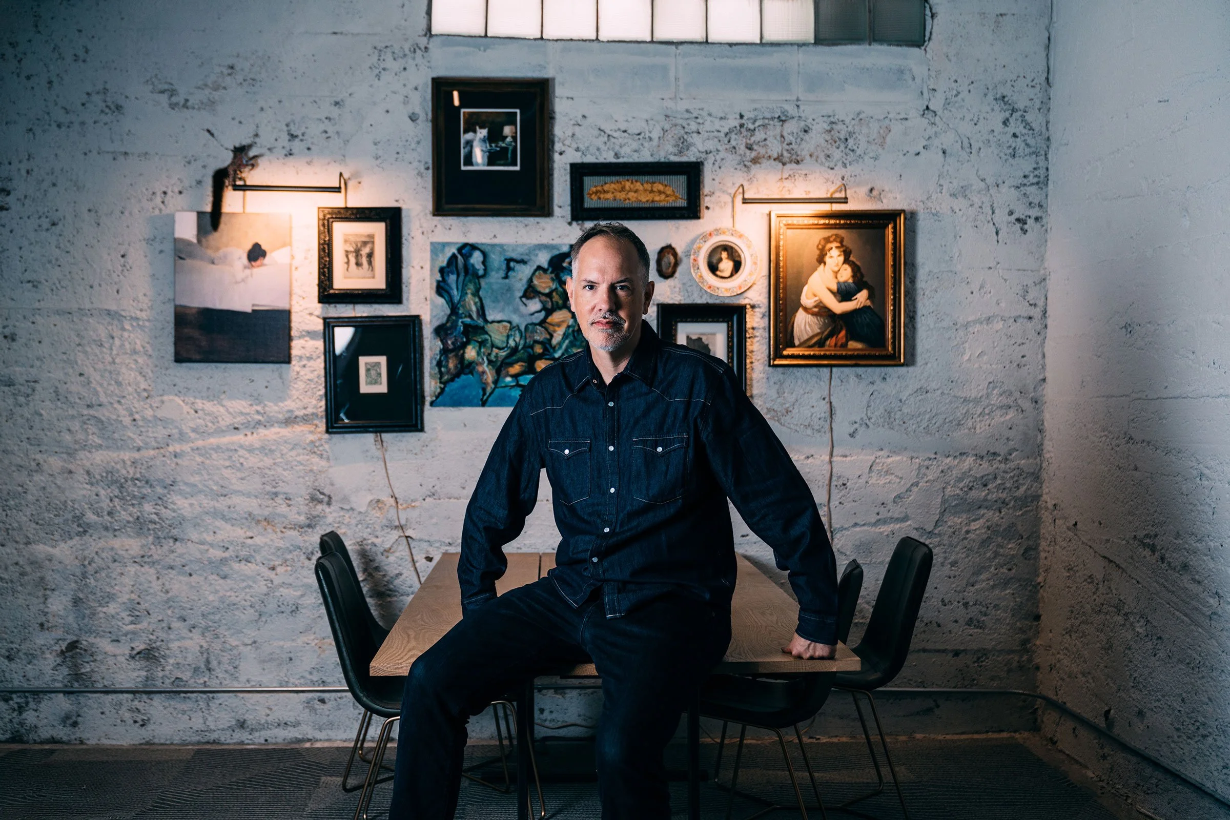 Dan at a table with paintings behind
