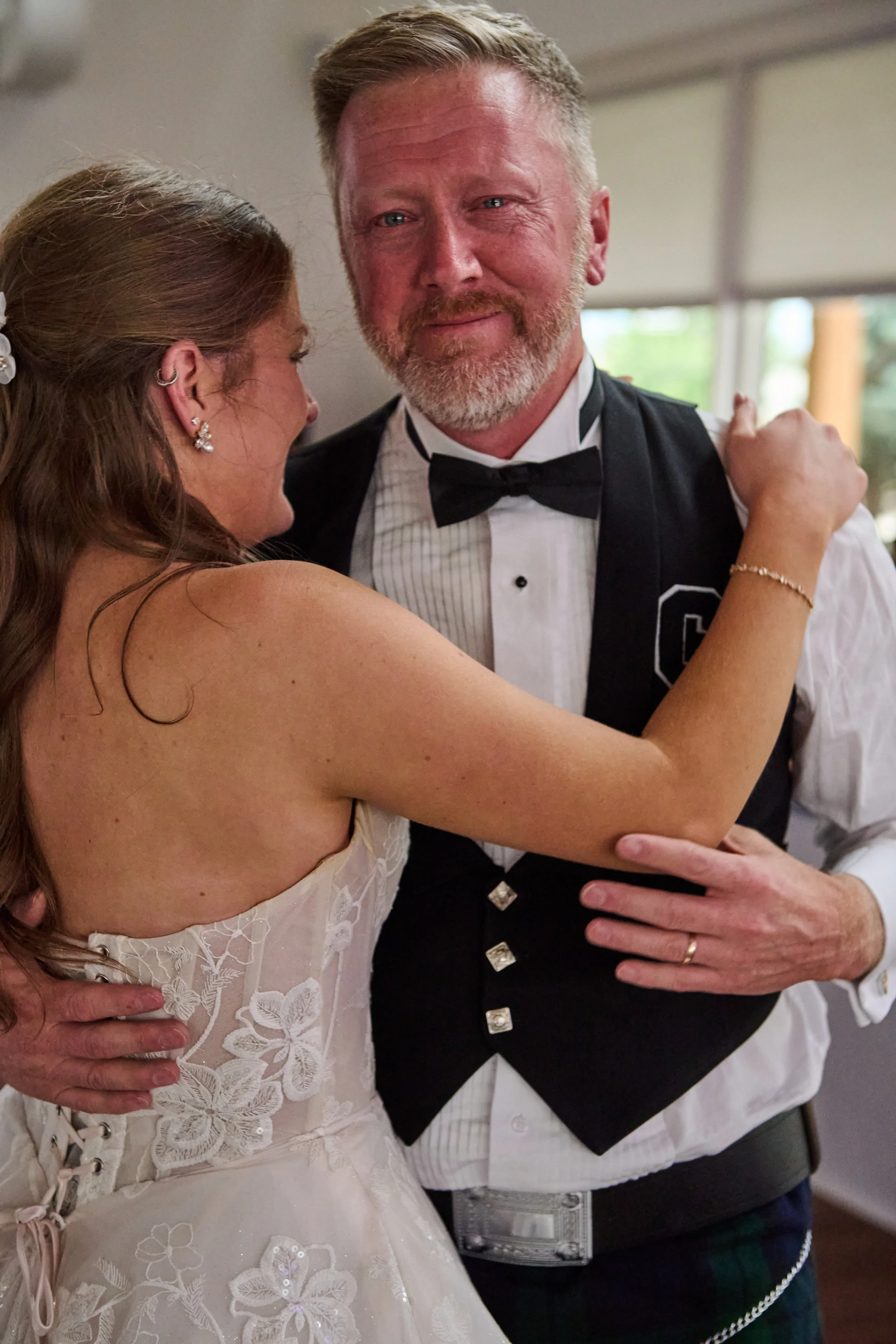 A bride and groom sharing a dance at their wedding reception, with the bride smiling and the groom looking content.