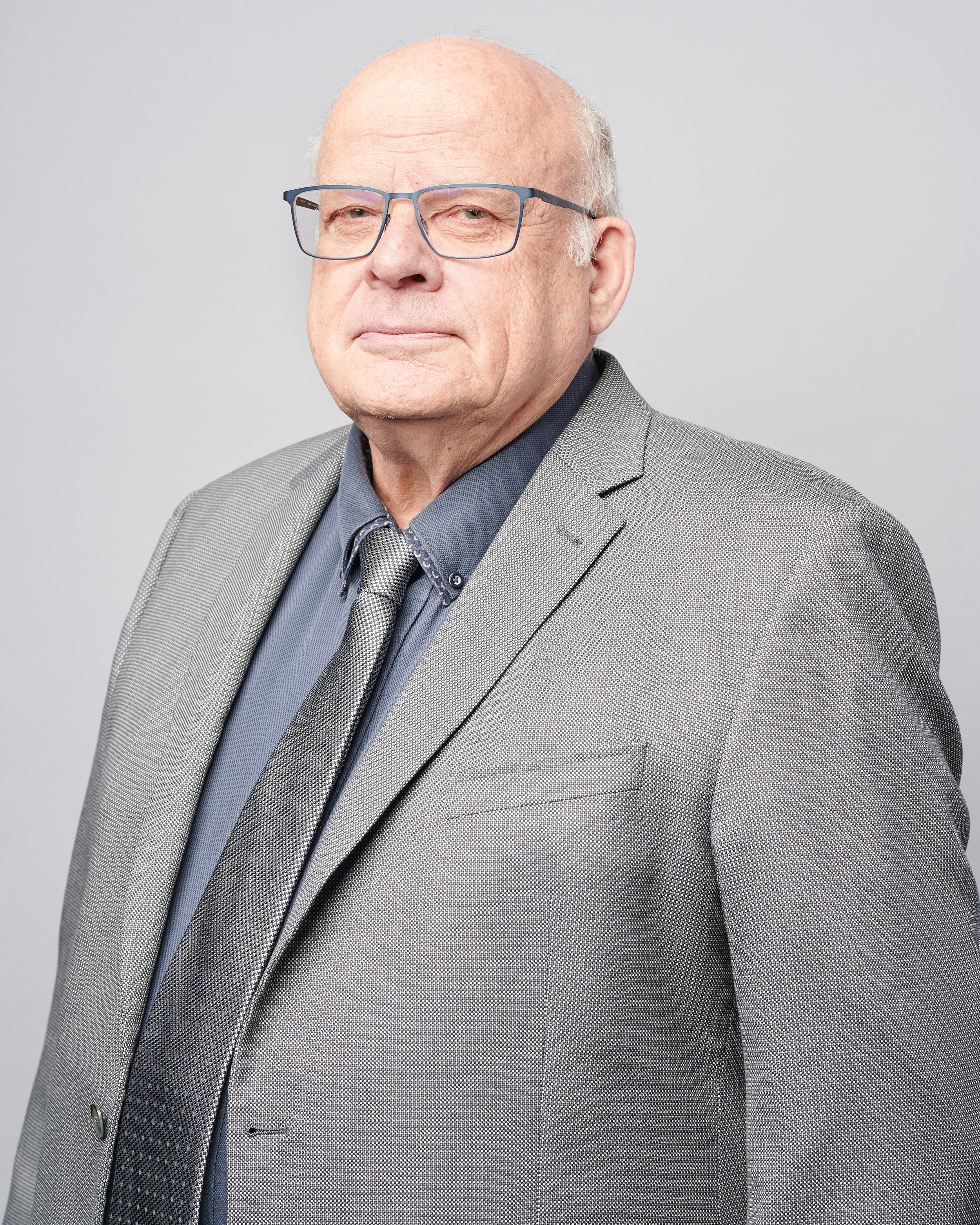 Elderly man with glasses wearing a suit and tie