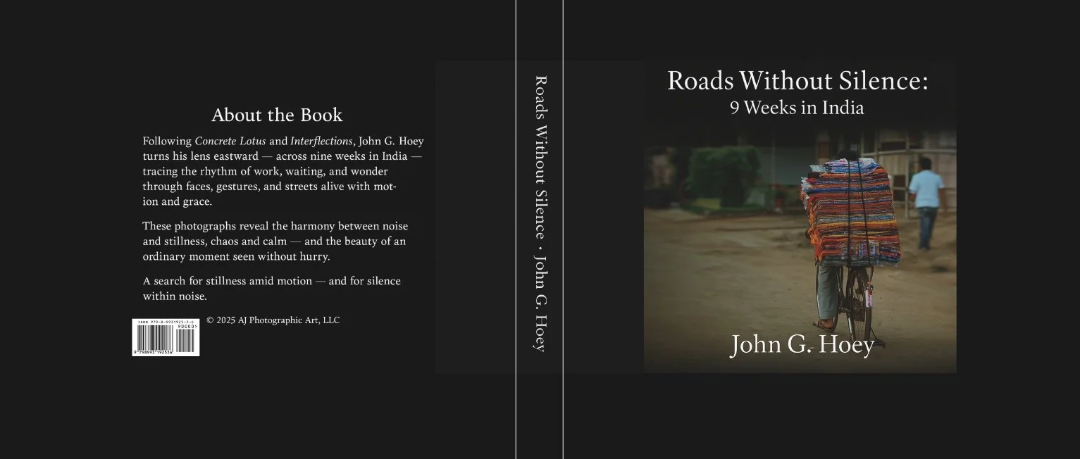 Cover of Roads Without Silence: 9 Weeks in India by John G. Hoey, showing a person carrying a tall stack of folded textiles on a bicycle, along with the book’s black back cover, spine, title, barcode, and author name.