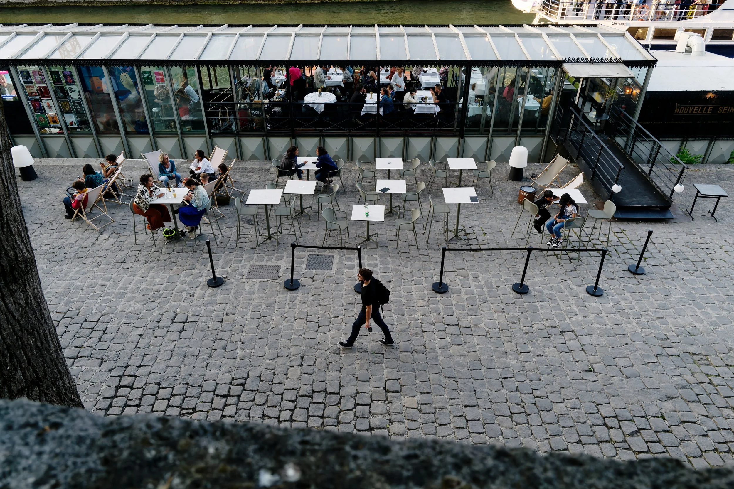 Between Gatherings (Paris)

Seen from above, a solitary figure crosses the cobblestones between small groups gathered at scattered tables and the denser social world of the restaurant beyond. His movement creates a quiet counterpoint to those who are