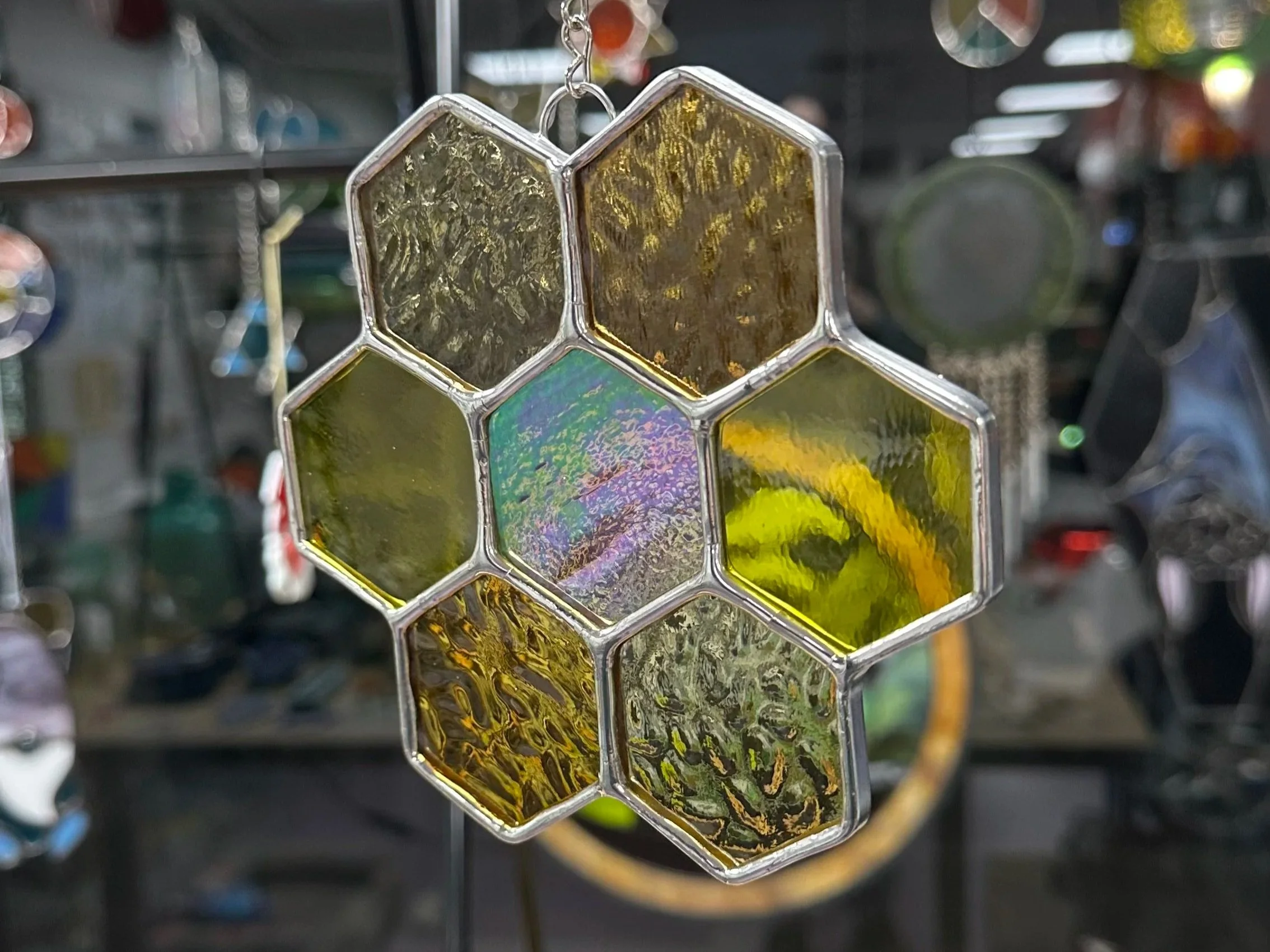 Honeycomb stained glass sun catcher that is made of beautiful ambers and yellows with iridescent glass and uses the copper foil method to solder and foil the pieces together for you to make in one class.