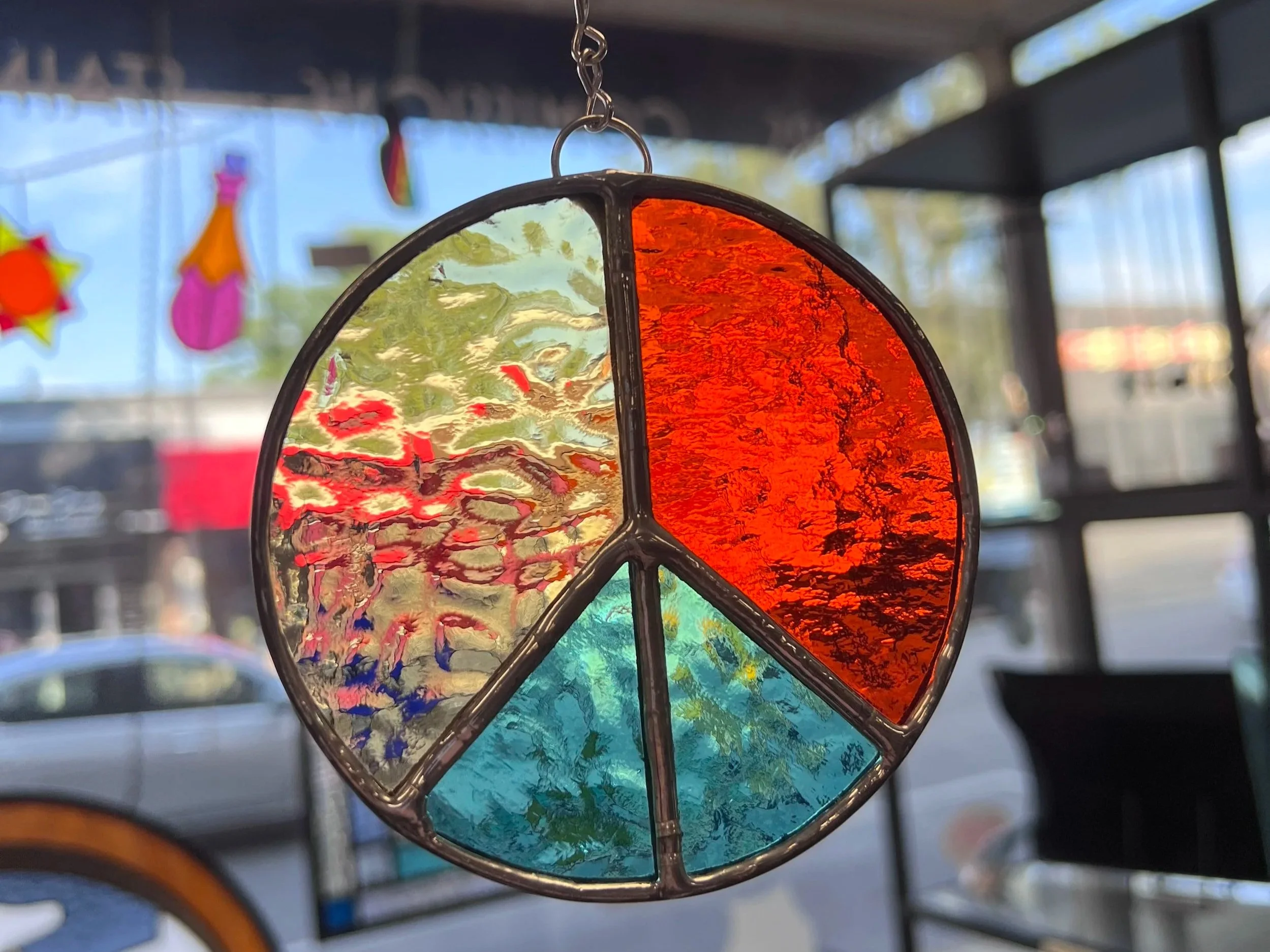 stained glass peace sign sun catcher/ ornament made in Stern Glass Works DIY workshop Glass in a Flash. the peace sign is made using the copper foil stained glass technique in oak park il outside of chicago illinois. this art glass is perfect gift