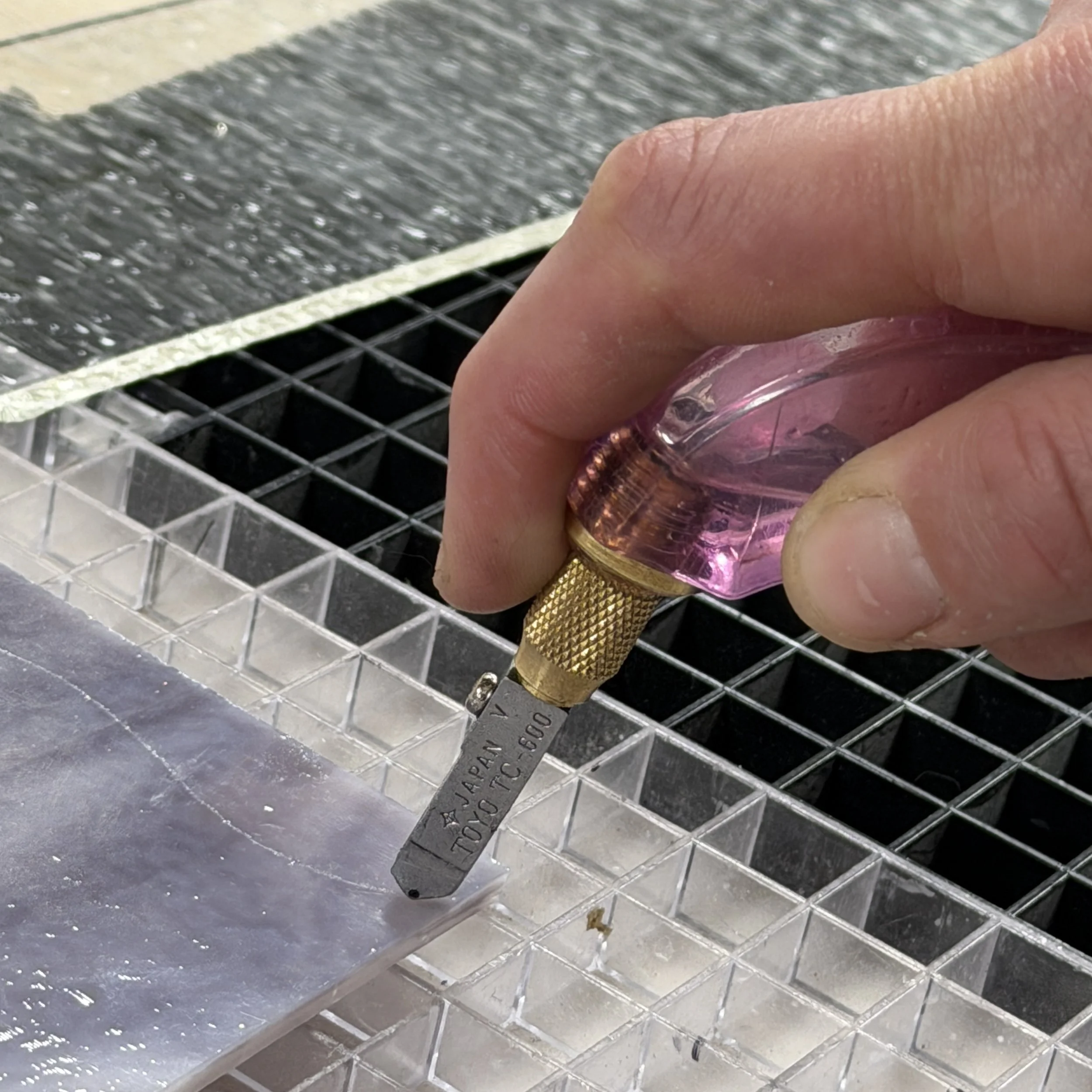 Person holding a pistol grip glass cuter cutting purple sheet glass at stern glass works 