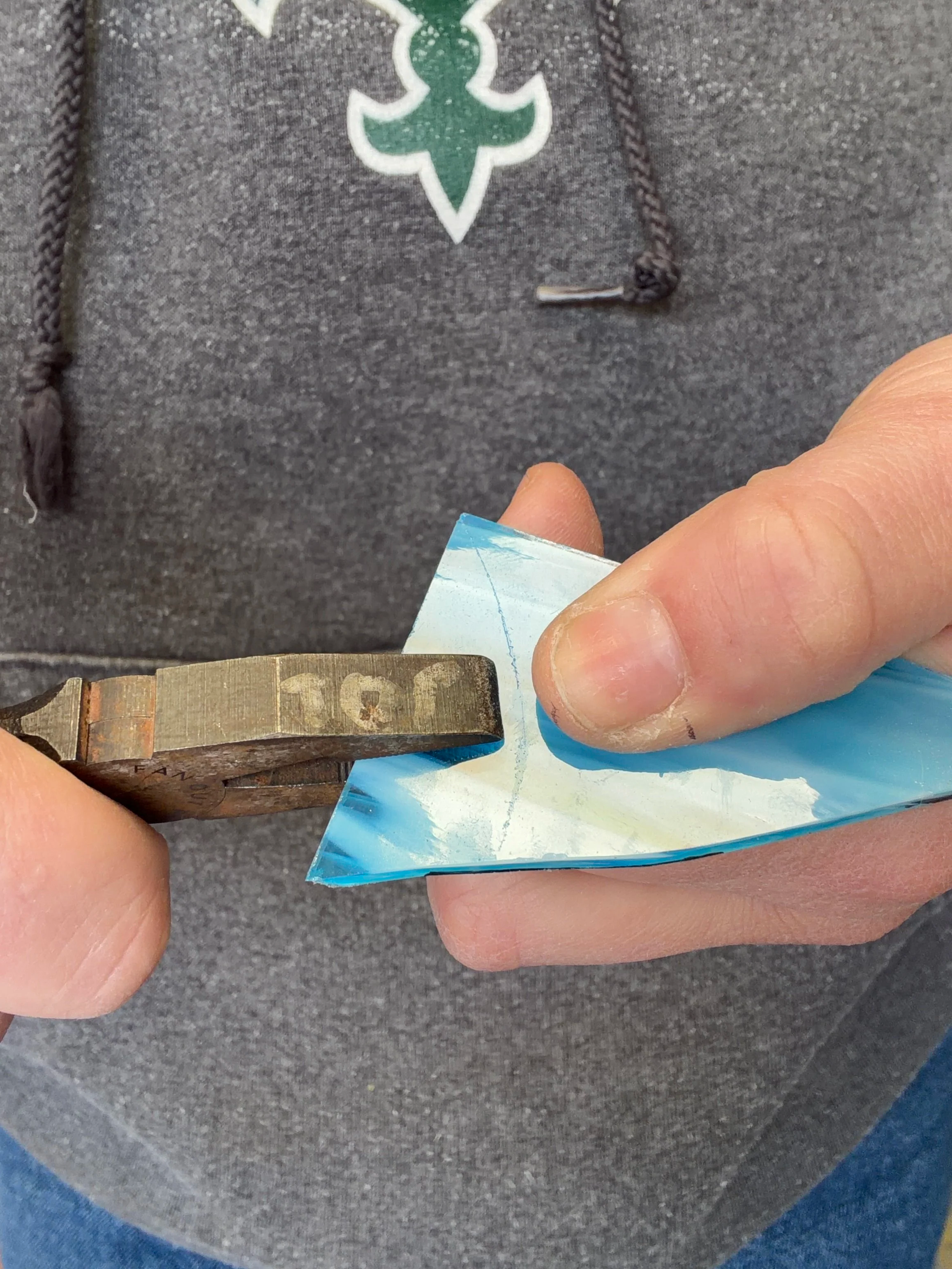 person cutting a blue piece of sheet glass using the grozing technique at stern glass works