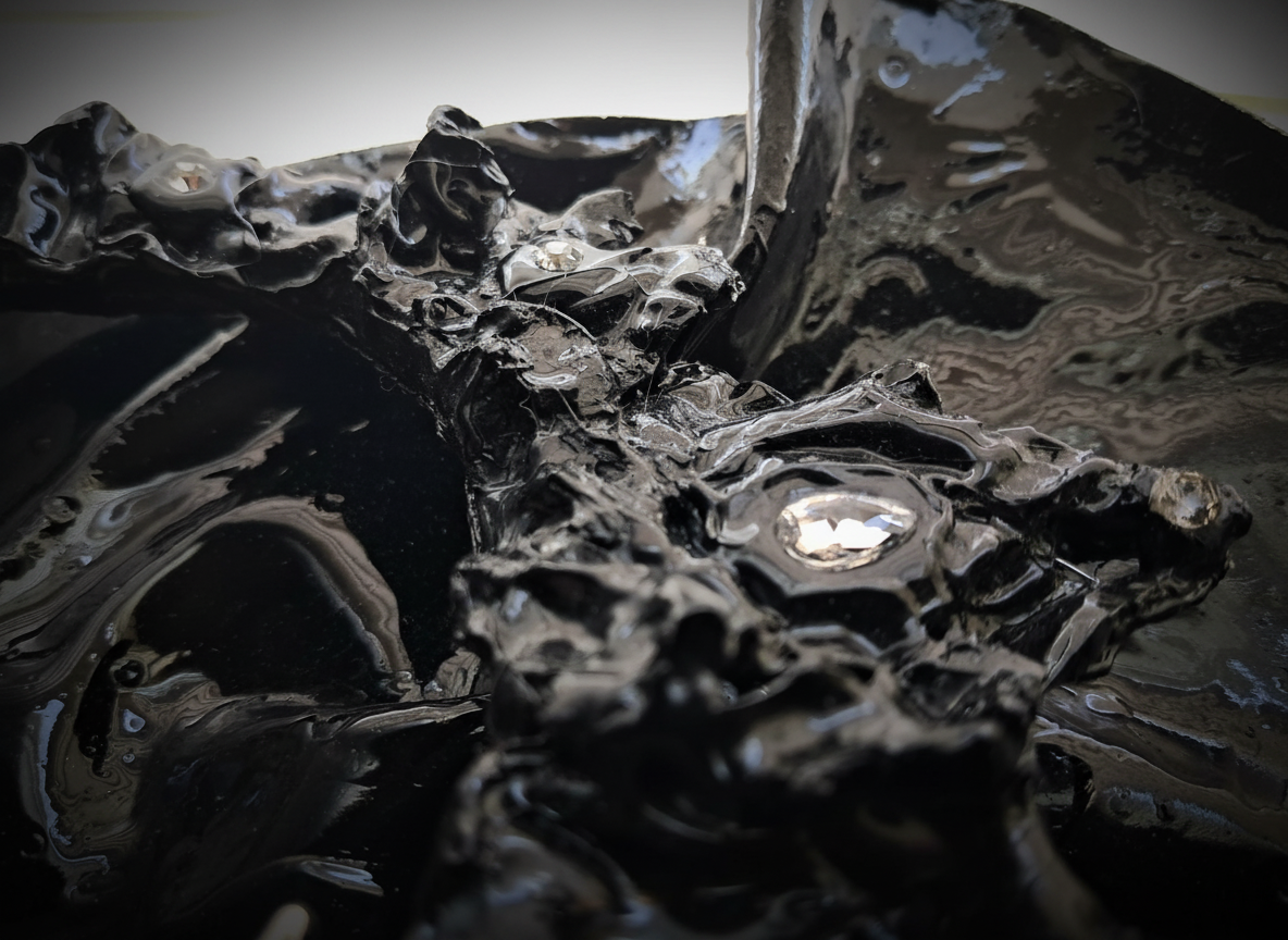 Close-up of a glossy black abstract sculpture with a textured, shiny surface.