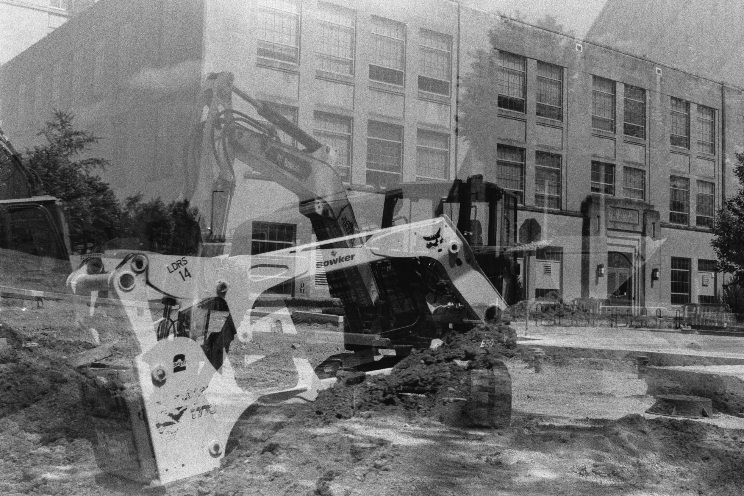 A construction site at the bottom of Dubuque Street Hill shows a Bobcat skid-steer loader and a Bowker excavator.