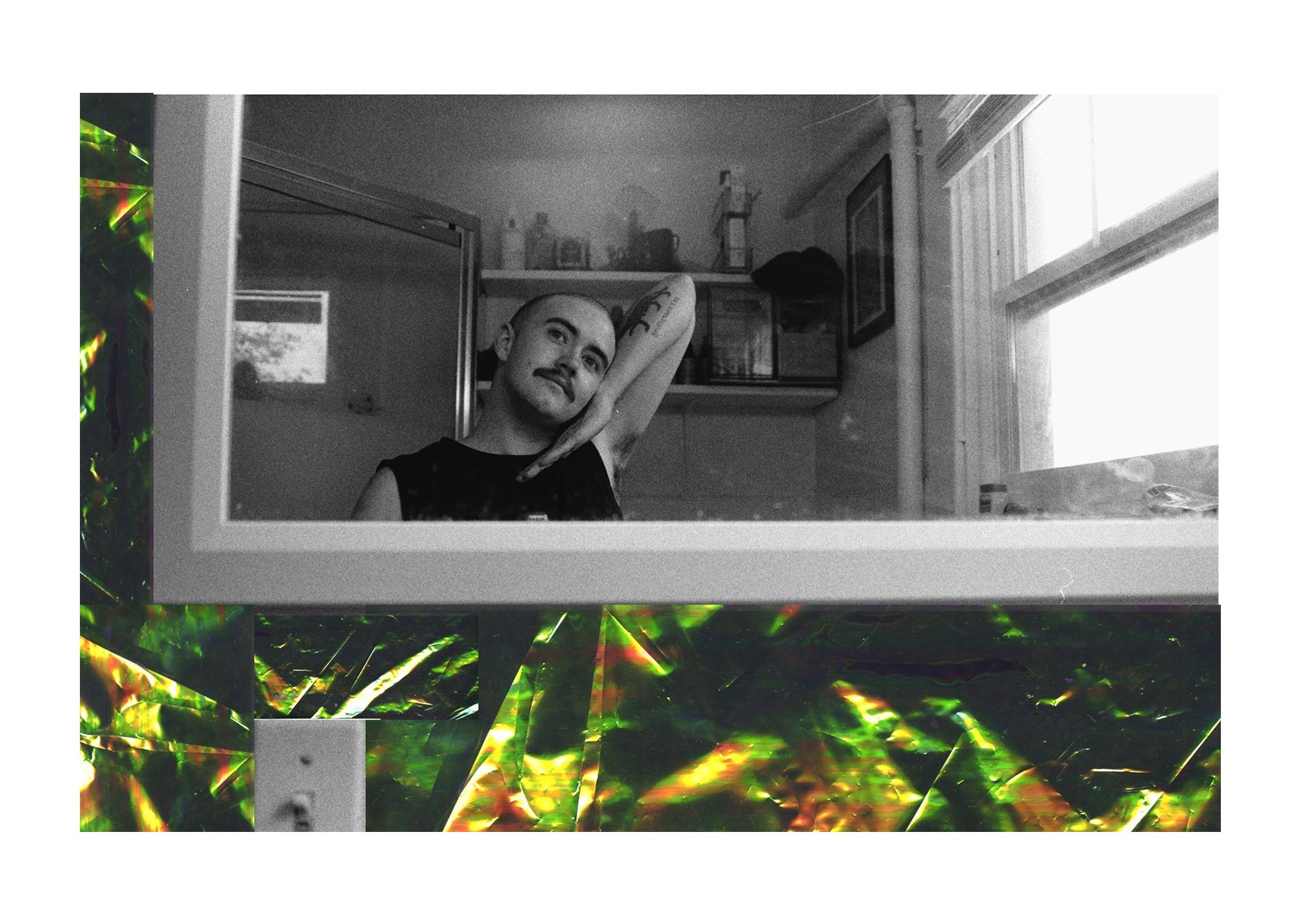 A black-and-white mirror portrait shows a transmasculine nonbinary person in a black tank top, smiling against a tattooed arm, framed by gold-green cellophane.