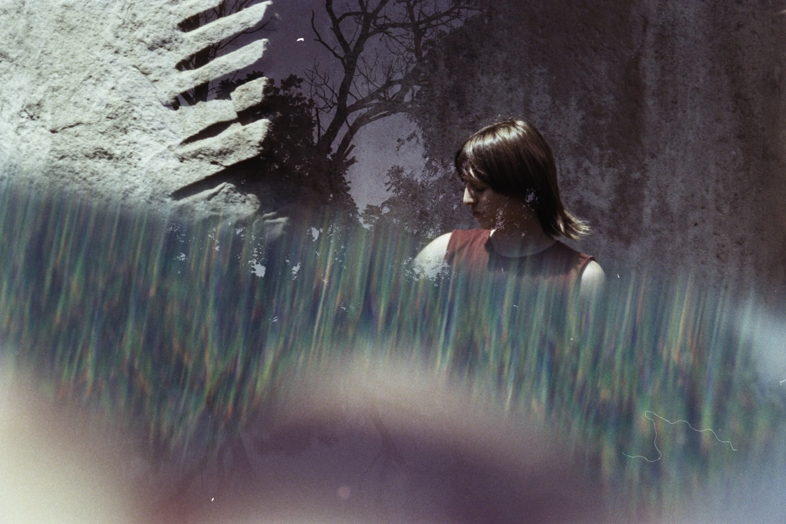 A short-haired woman in a red shirt looks down in profile by Hancher’s stone blocks, with a colorful prism and a second exposure of a tree.