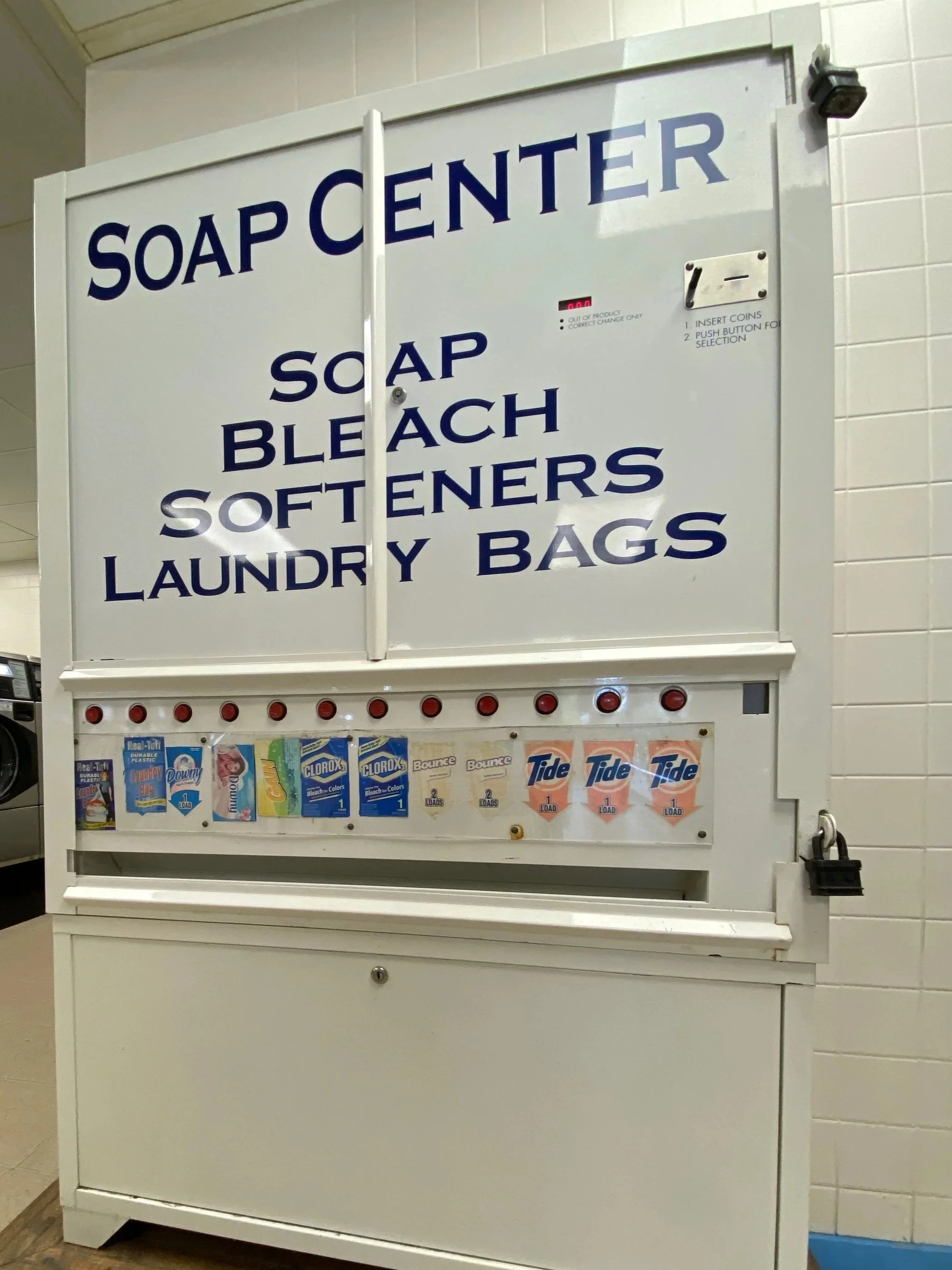 A vending machine labeled 'Soap Center' with soap, bleach, softeners, laundry bags, and detergent options.