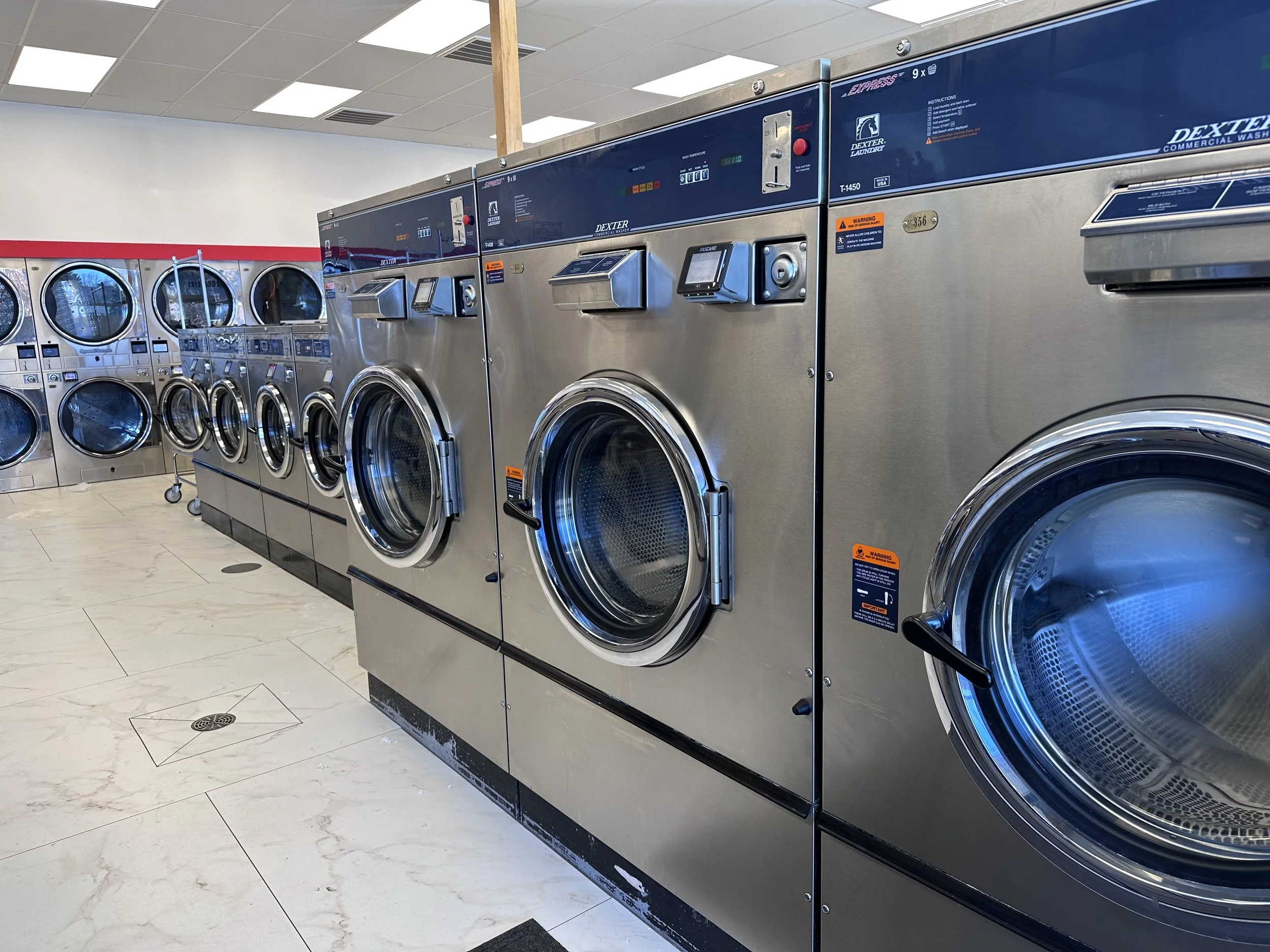 Multiple commercial washing machines in a laundromat.