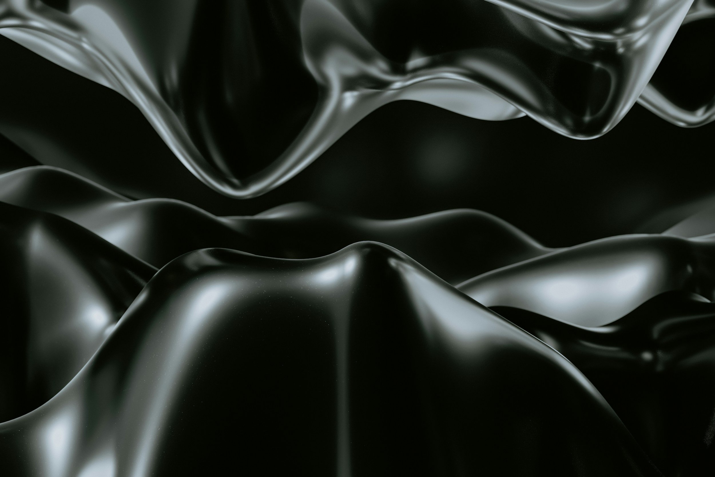 Close-up of black, shiny, smooth, metallic or plastic material with flowing, organic curves and folds.