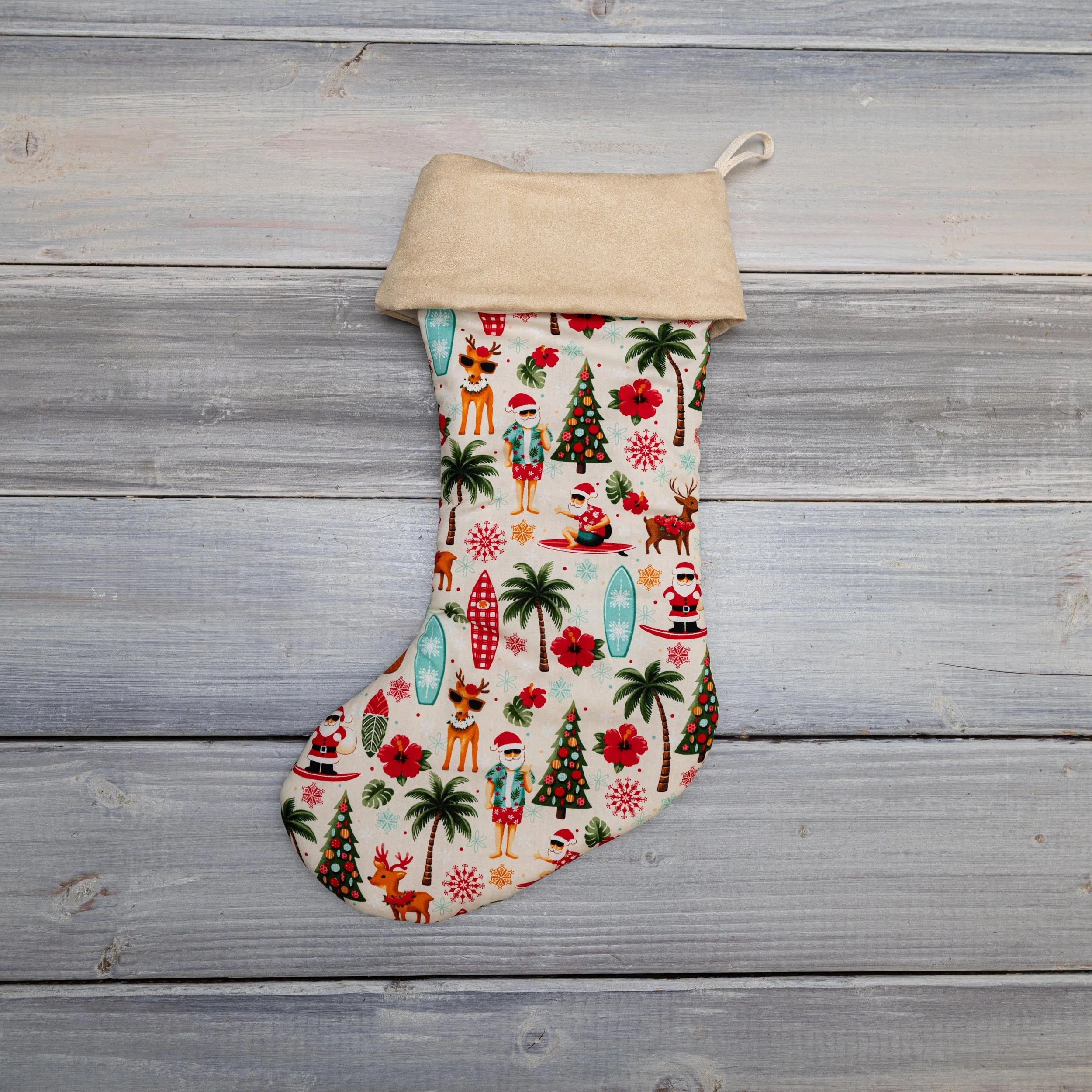 A Christmas-themed fabric stocking with a beige cuff, lying on a weathered wooden surface.