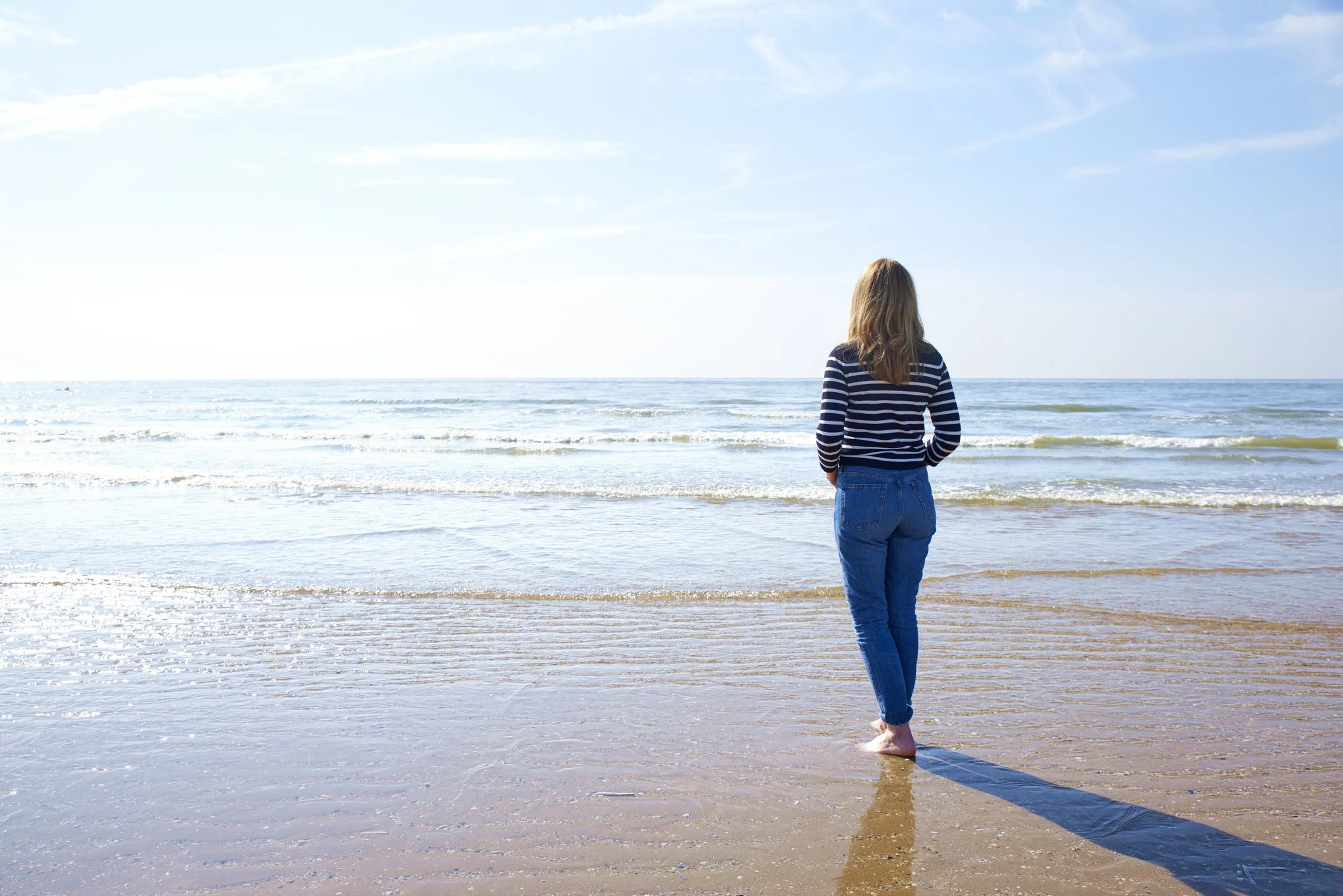 Woman walking slowly along the shoreline.