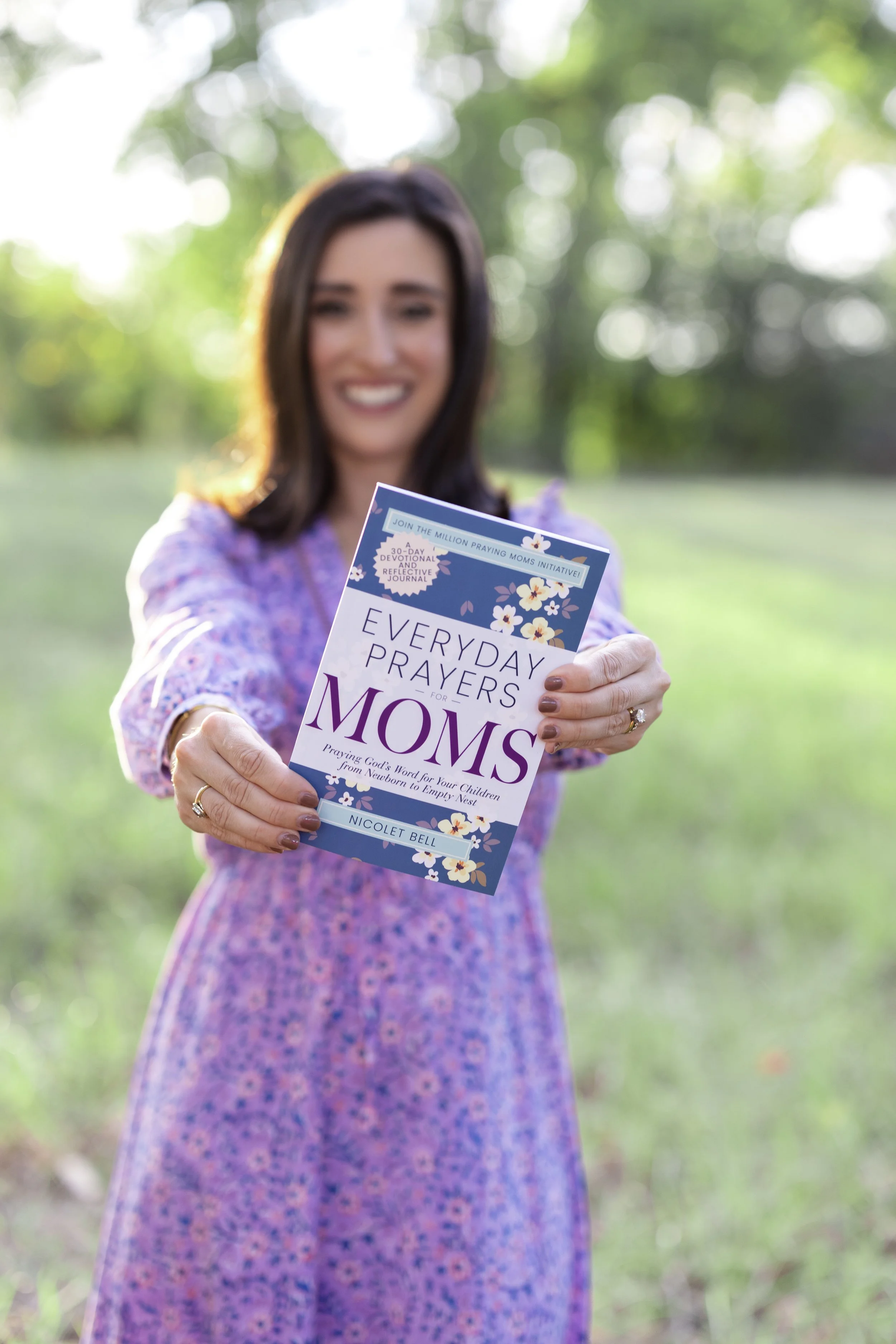 Nicolet Bell holding out Everyday Prayers for Moms book.