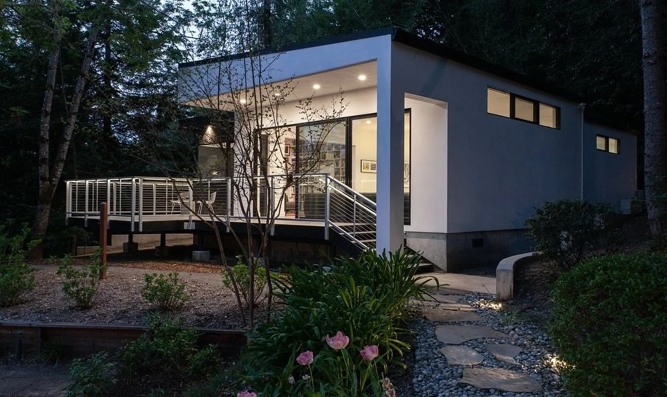 Tucked into a wooded slope in Forestville, this sleek 1,200 sq. ft. building reimagines the pool house. Featuring a bold white stucco volume paired with a Shou Sugi Ban charred wood clad cube, its design merges sharp geometry with thoughtful function