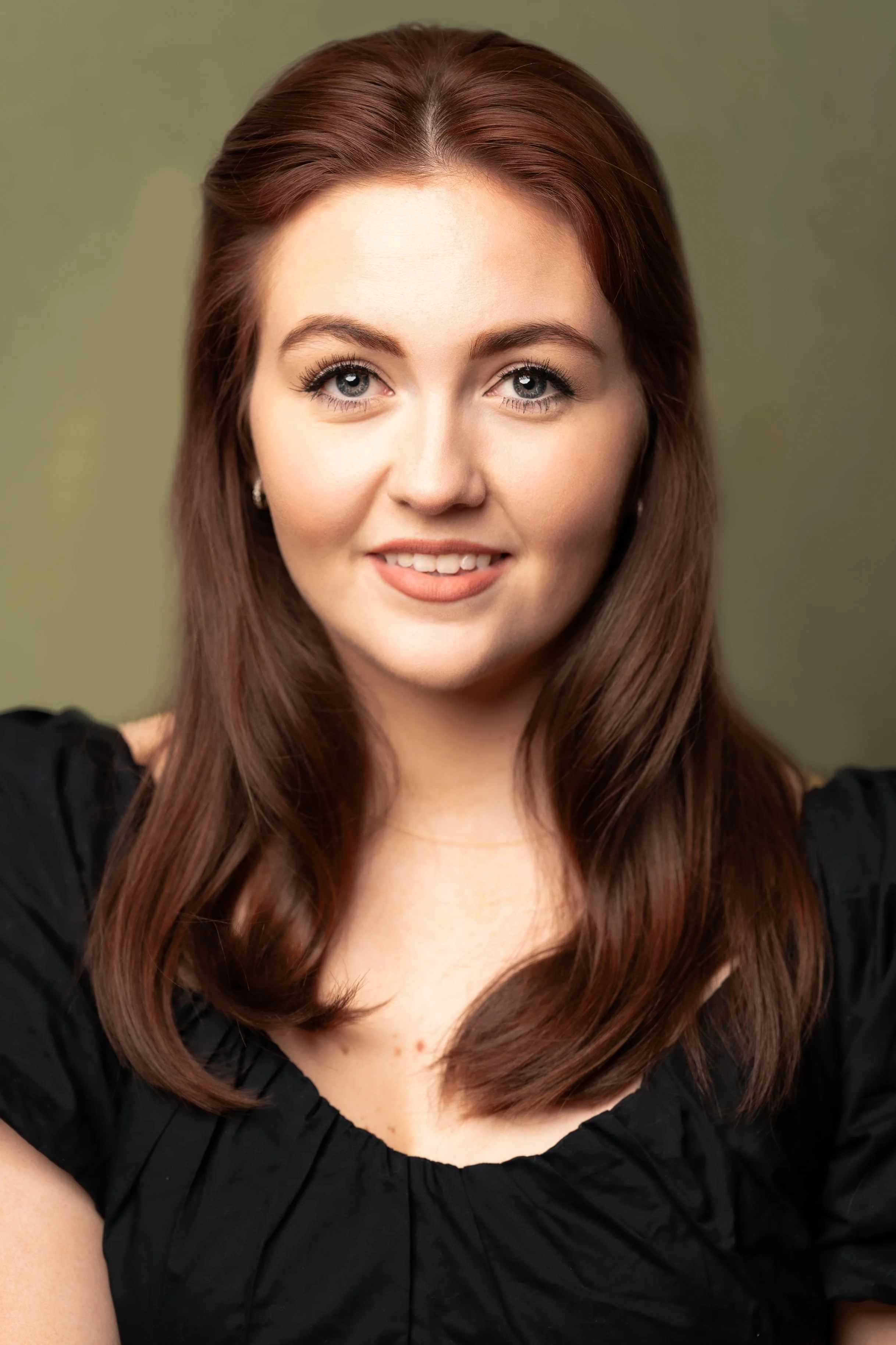 Smiling person with red hair wearing a black top. Payton Steffensen. Jacob Goz Photography Musical theatre headshot