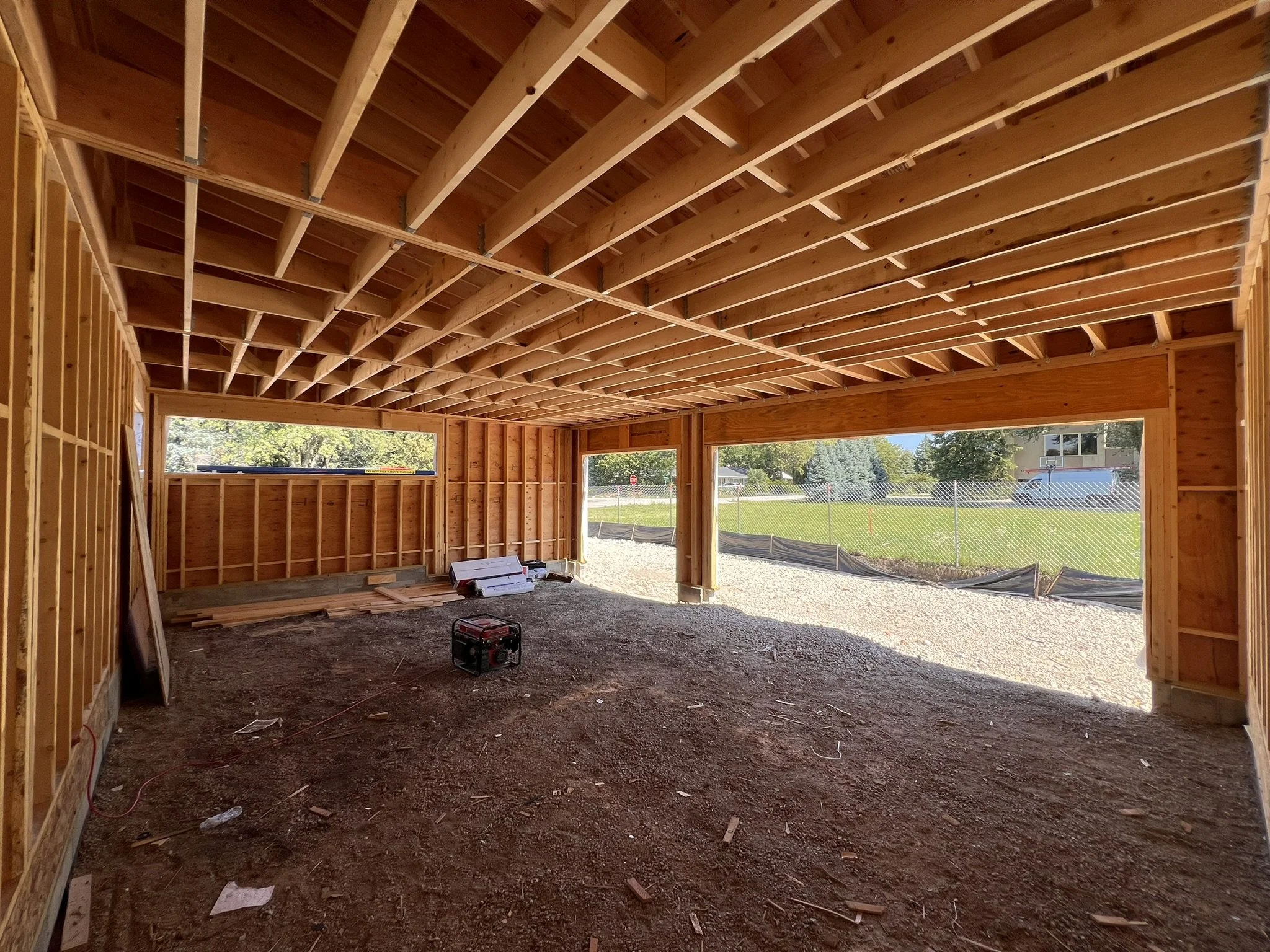 Coorlas Architecture luxury modern interior under construction with exposed wooden framing, stairs, large windows, and expansive tall spaces with long beam spans.