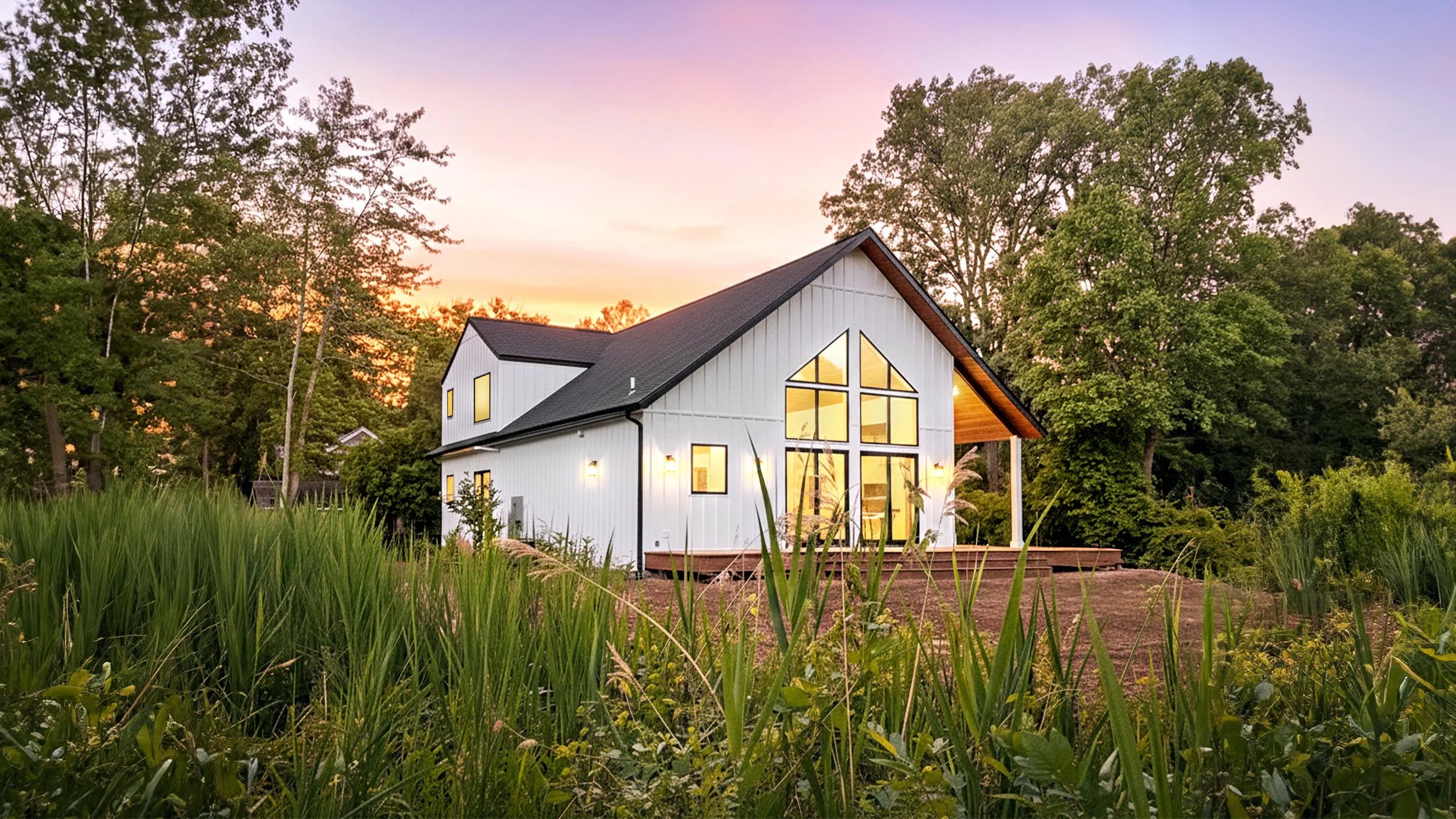 Coorlas Architecture modern farmhouse new construction two-story lake house in Lakeside, Michigan. The home features white board and batten siding, a black asphalt shingle roof, aluminum plank wood siding, large windows, cedar soffit, and wood deck.
