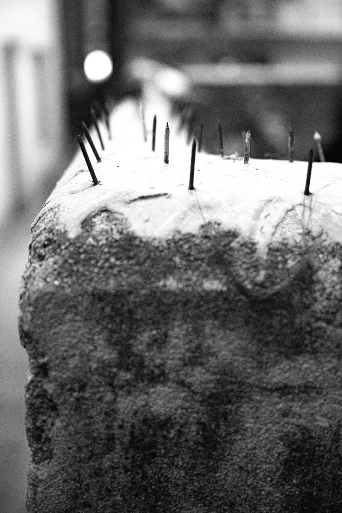 Nails serving as some form of deterrent on top of a roughly chest high wall