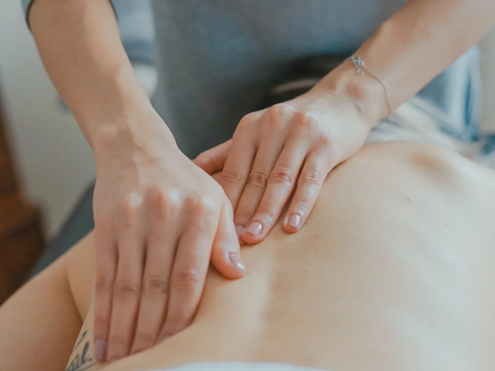 A specialized massage therapist performing a gentle lymphatic drainage massage on a client's back to reduce swelling and promote circulation at Blue Sky Massage in Winter Park, Colorado.