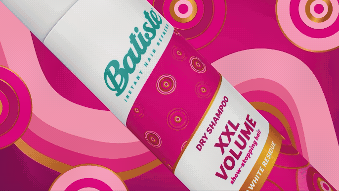 A bottle of Batiste dry shampoo with a pink and white design, featuring concentric circles in shades of pink, orange, and yellow.