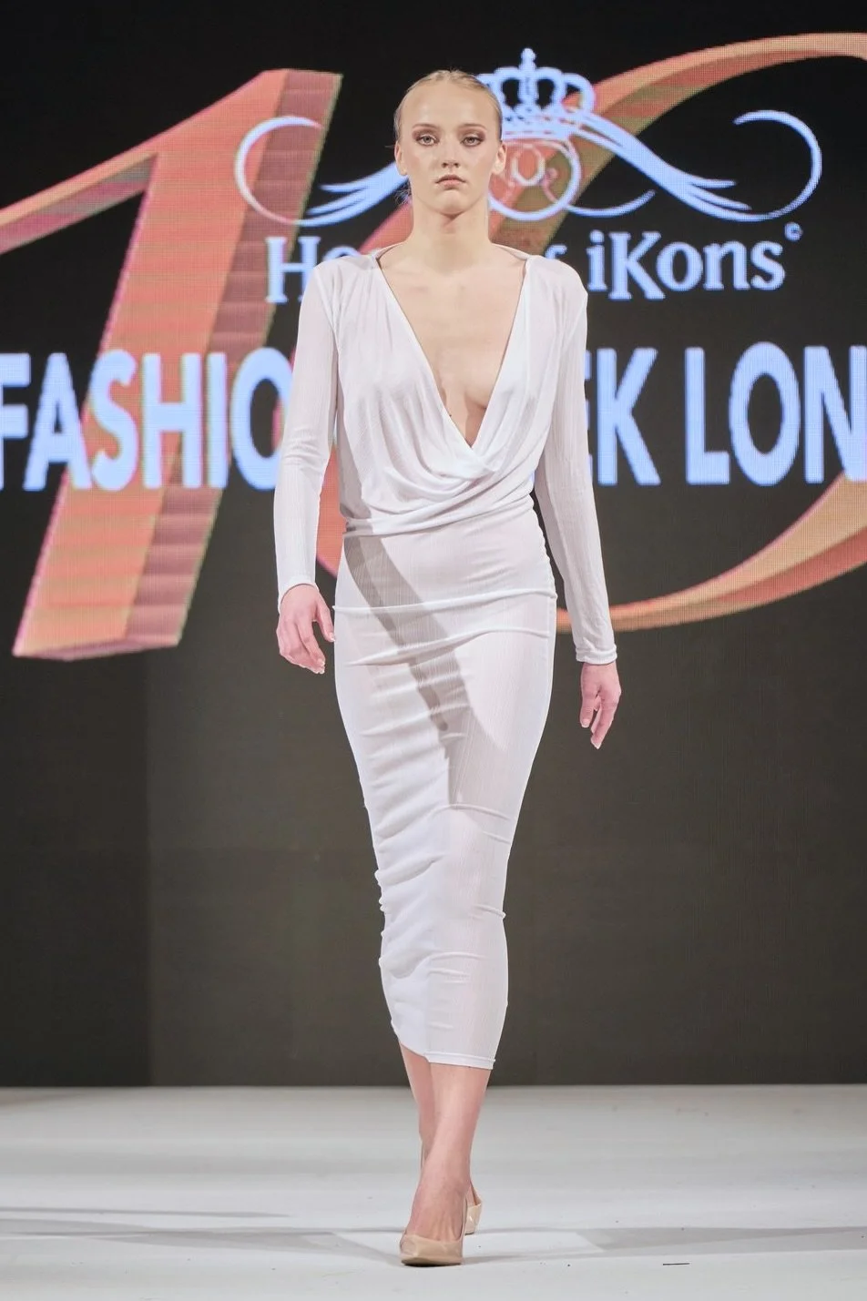 Model walking on runway during fashion show.