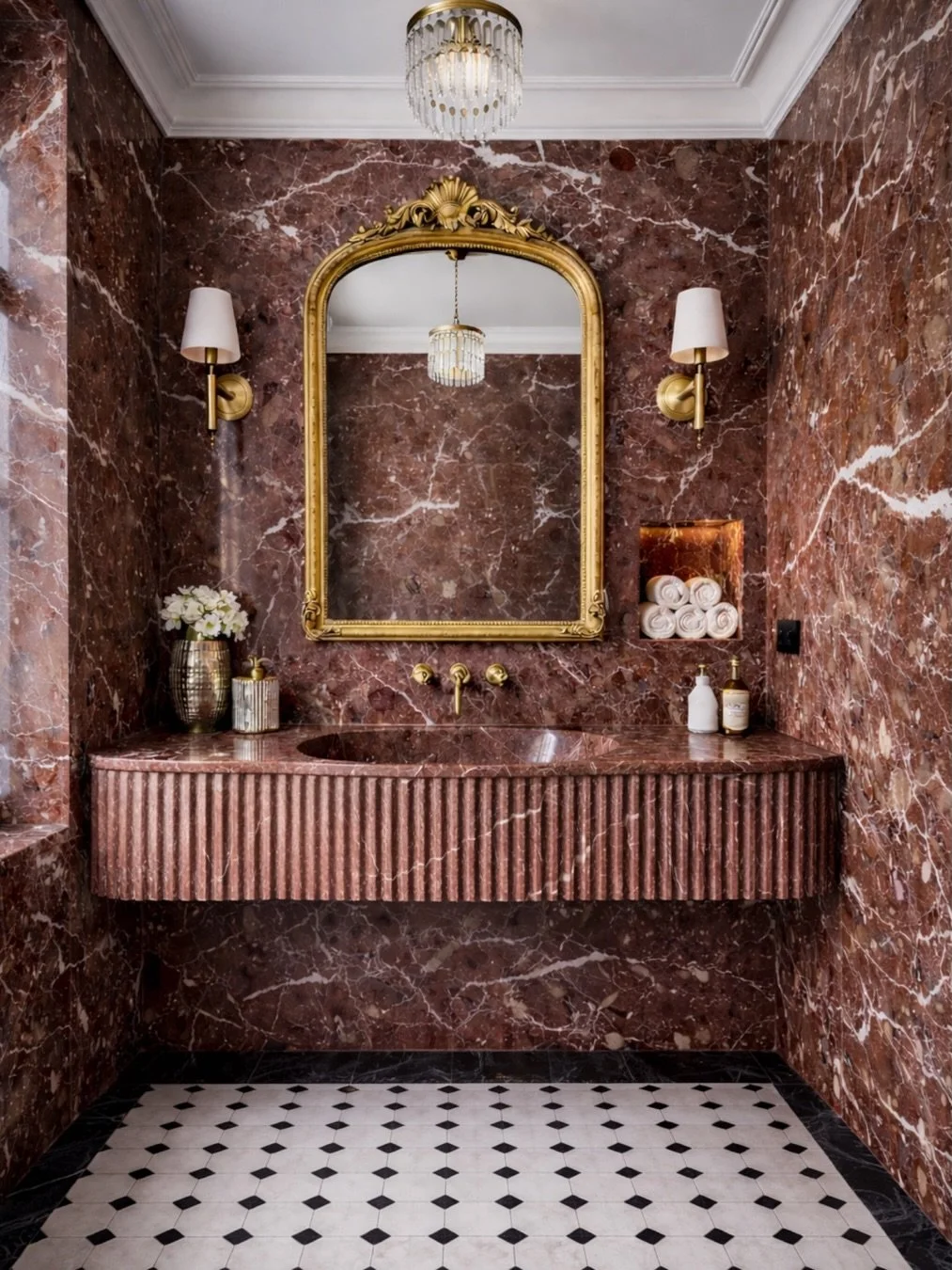 Designed by @yeginfill, a jewel-like powder room wrapped entirely in Rosso Levanto marble, where a sculptural fluted vanity and gilded vintage mirror create an opulent Parisian moment of timeless craftsmanship and quiet drama.

Interior Design: @yegi