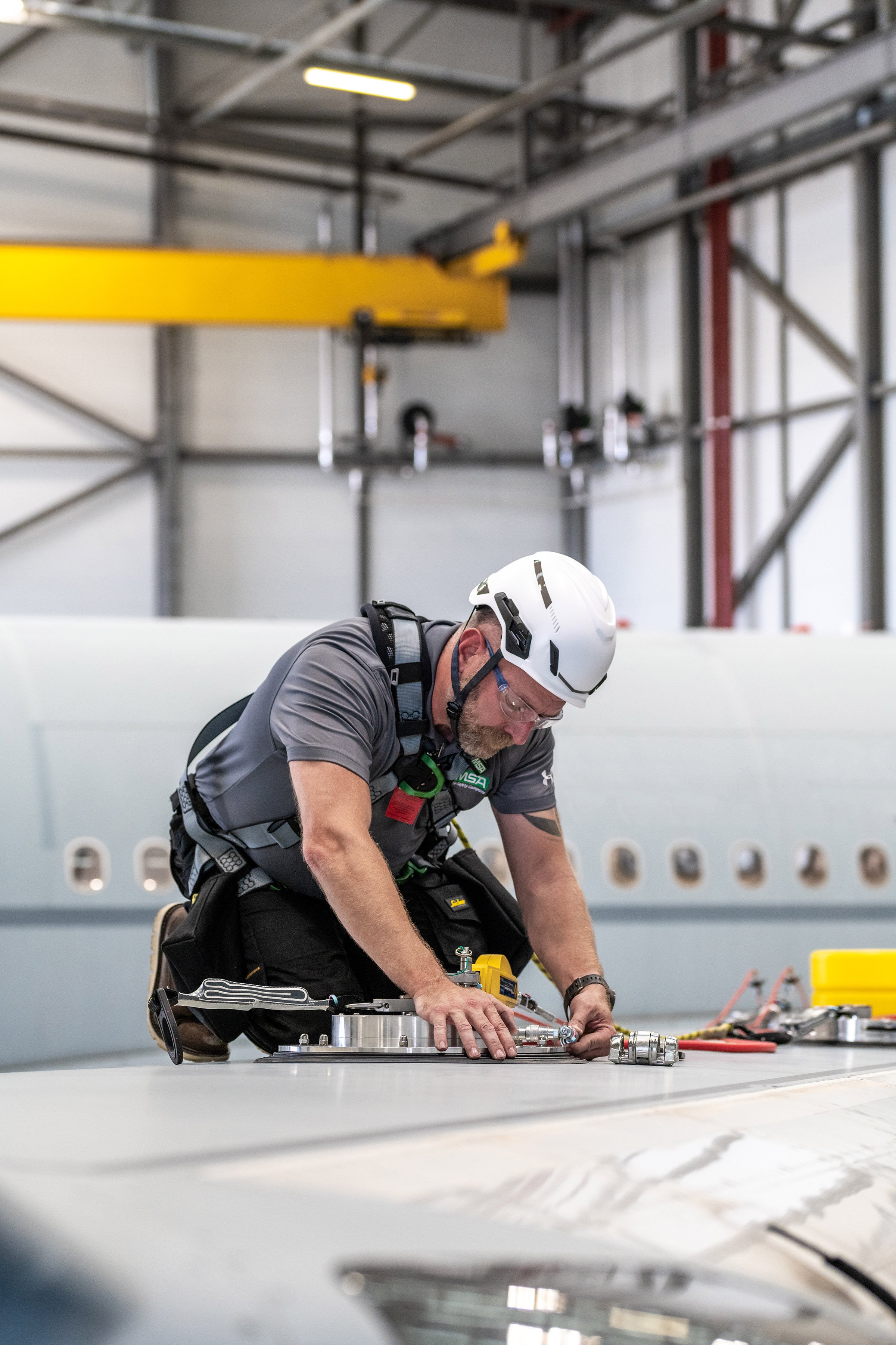 A technician uses WinGrip® Fall arrest equipment whilst working on the wing of an aircraft. Photographed for MSA Ltd