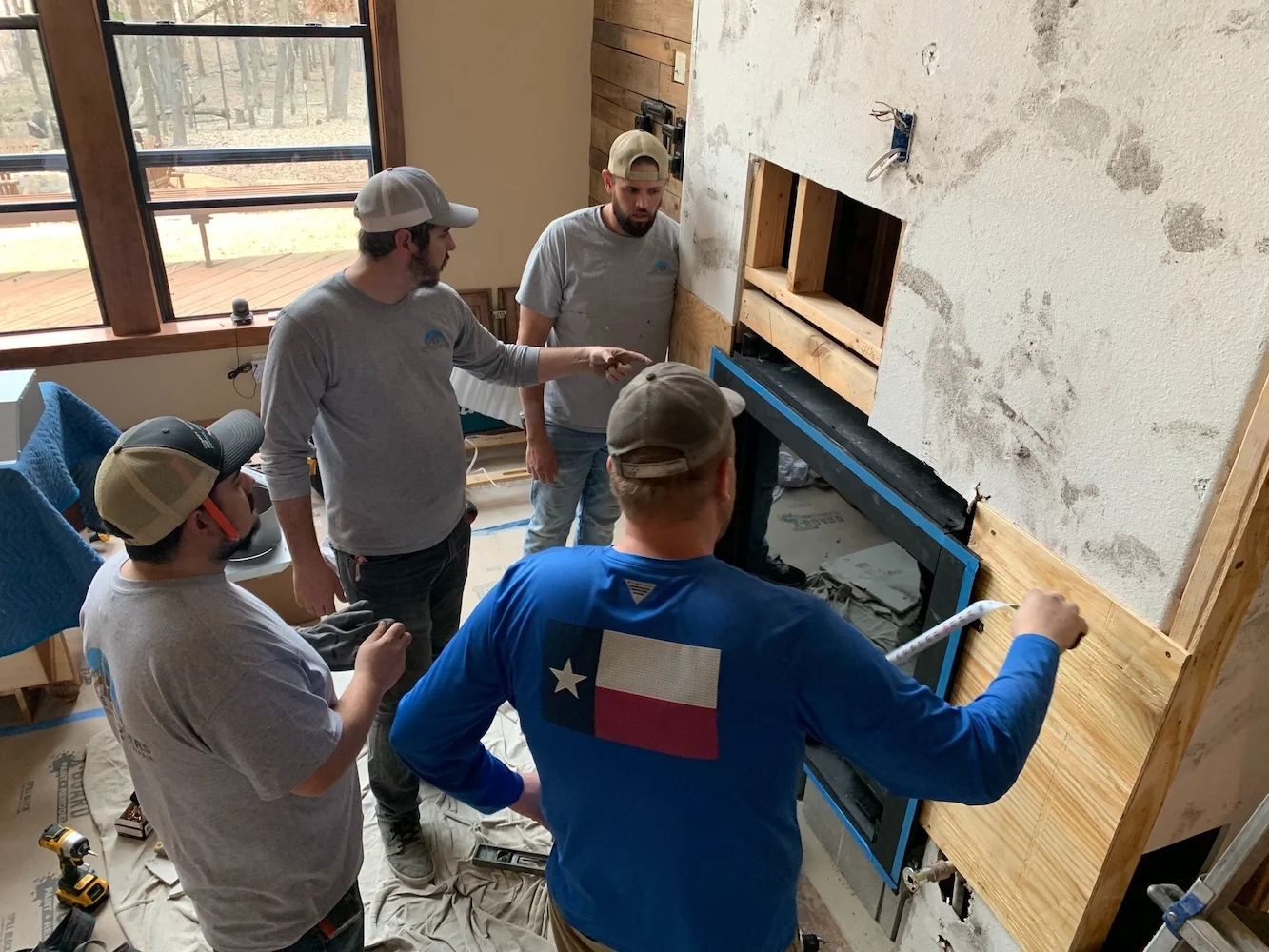 Sweeps N Ladders crew collaborating on a fireplace remodel installation, framing and fitting a new firebox during a full interior renovation.