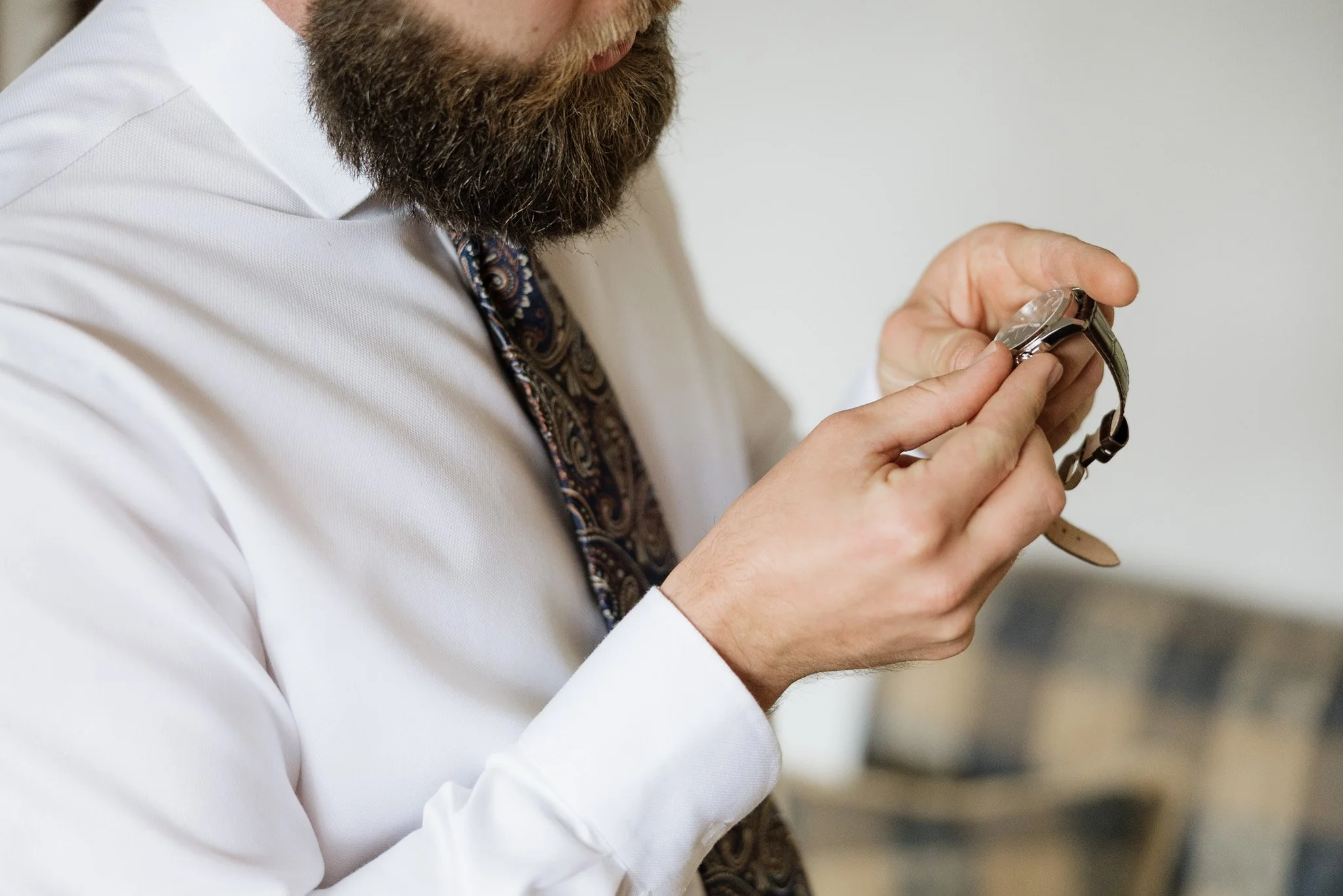 A man with a beard looking at his wristwatch.