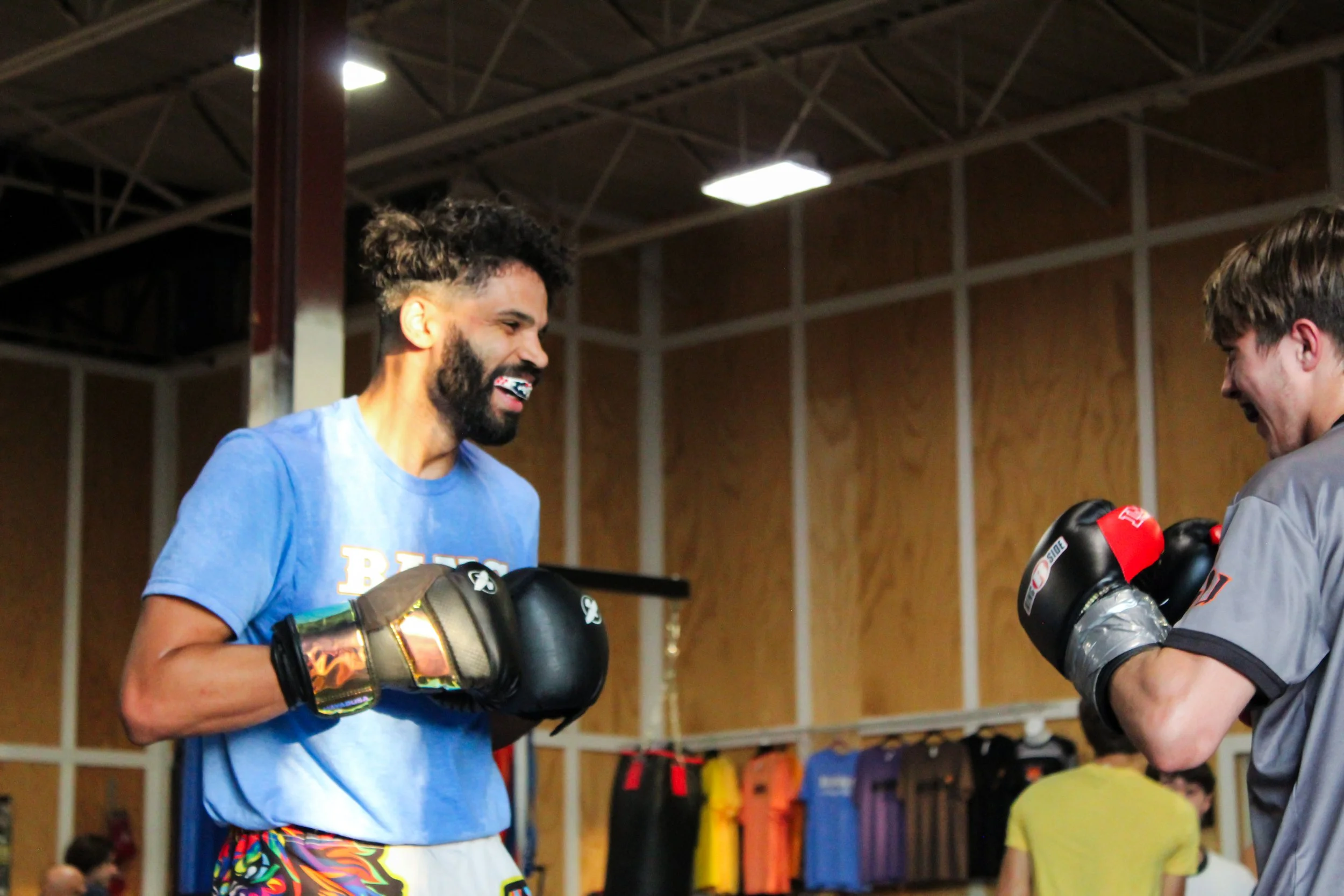 Two men in boxing gloves smiling and practicing boxing in a gym.